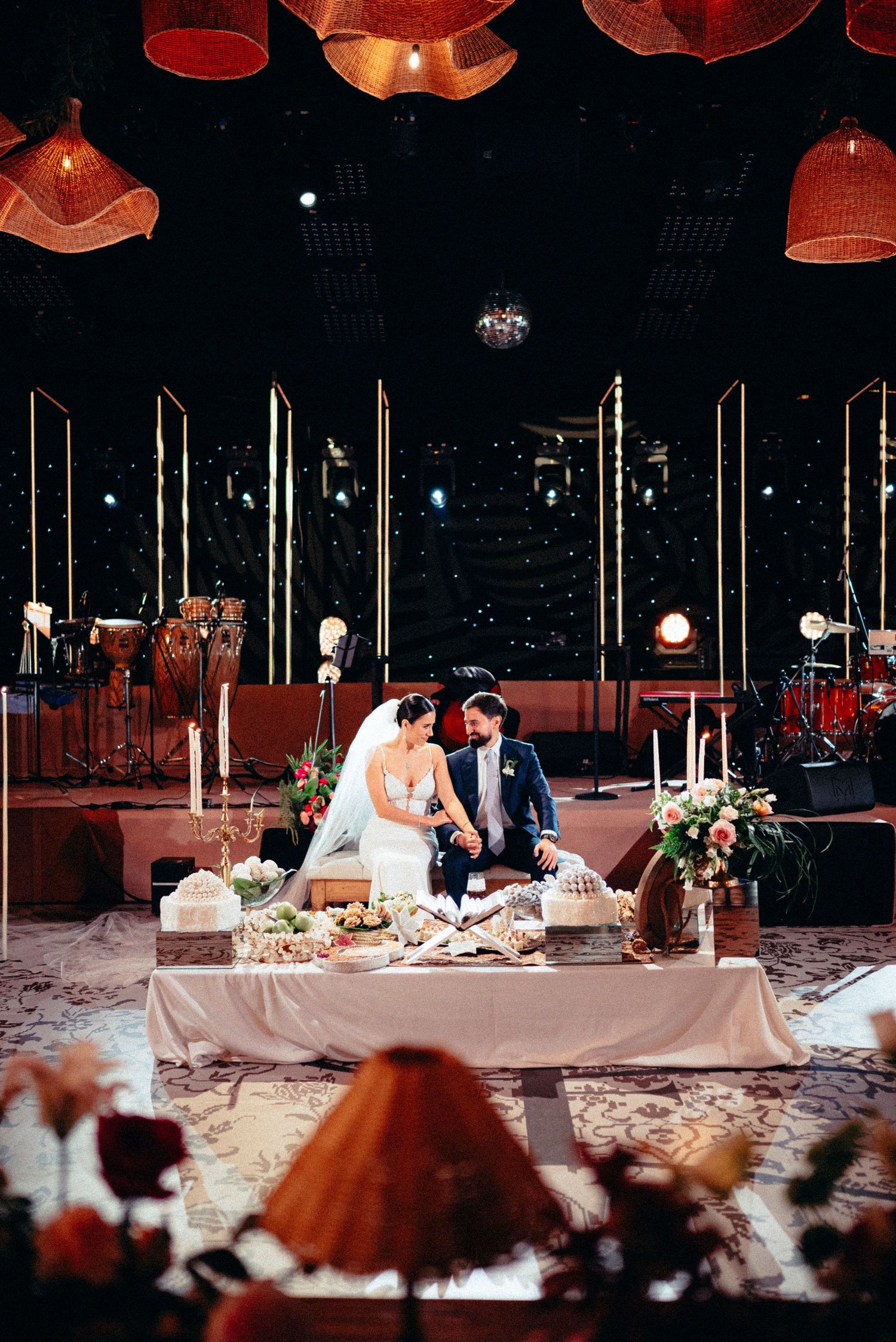 Bride and groom share an intimate moment at a candlelit sweetheart table during an elegant wedding reception.