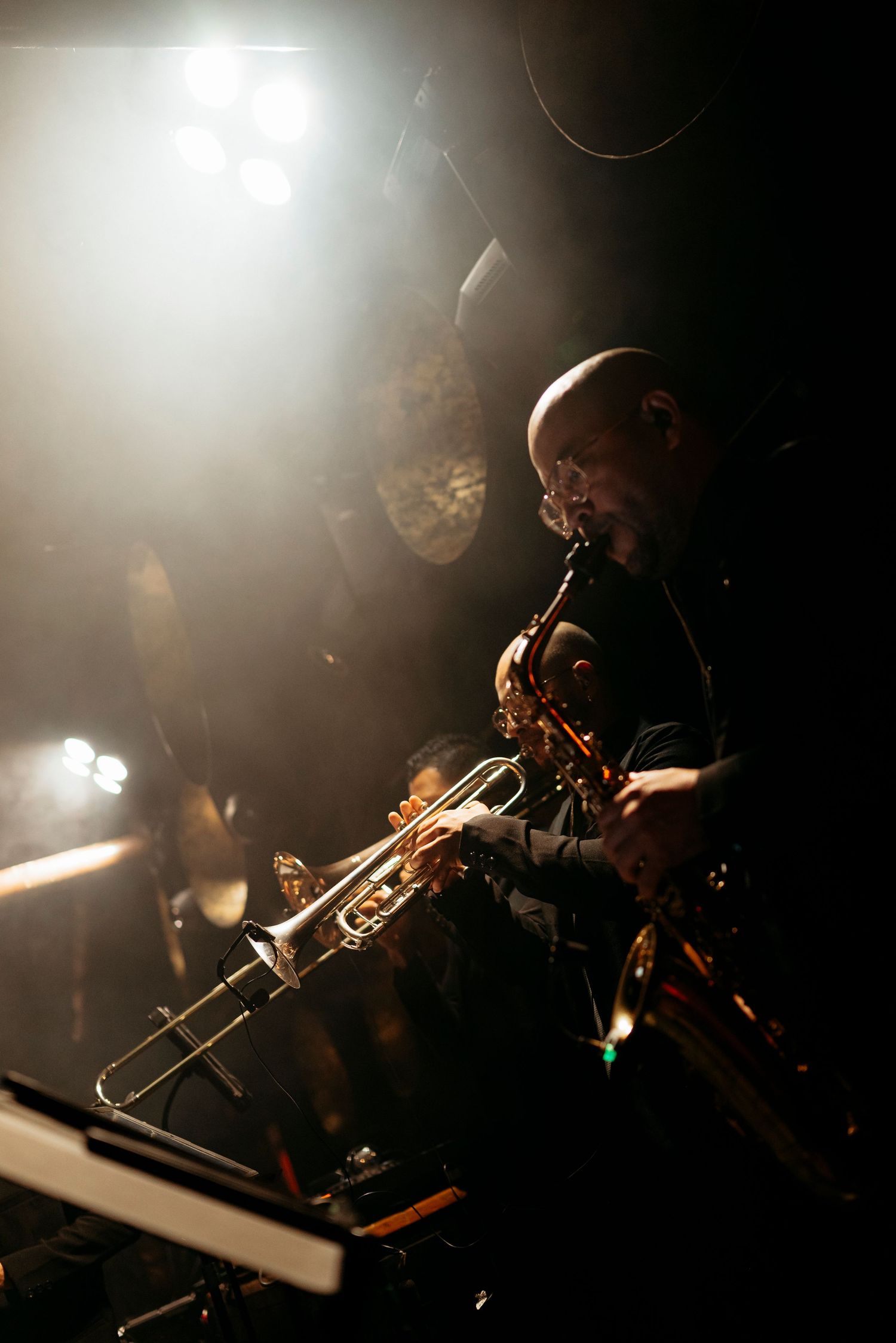 Jazz musician playing trumpet on a dimly lit stage with dramatic spotlight during a live performance.