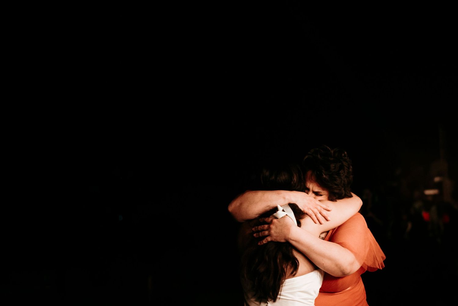 Two people in a passionate embrace dance together against a dark background.