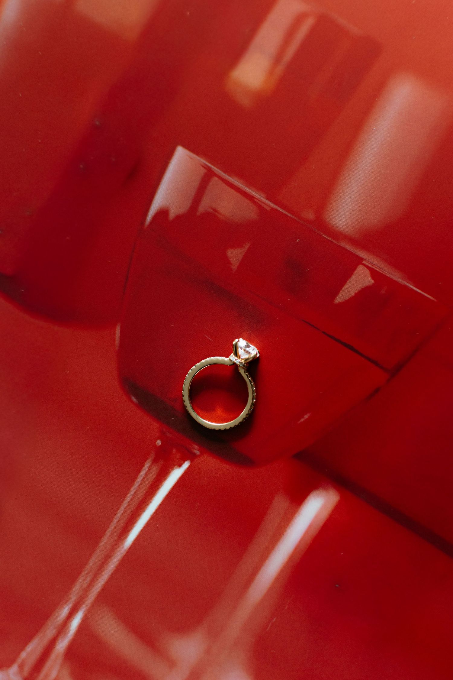 Close-up of engagement rings on a vibrant red surface with dramatic lighting.