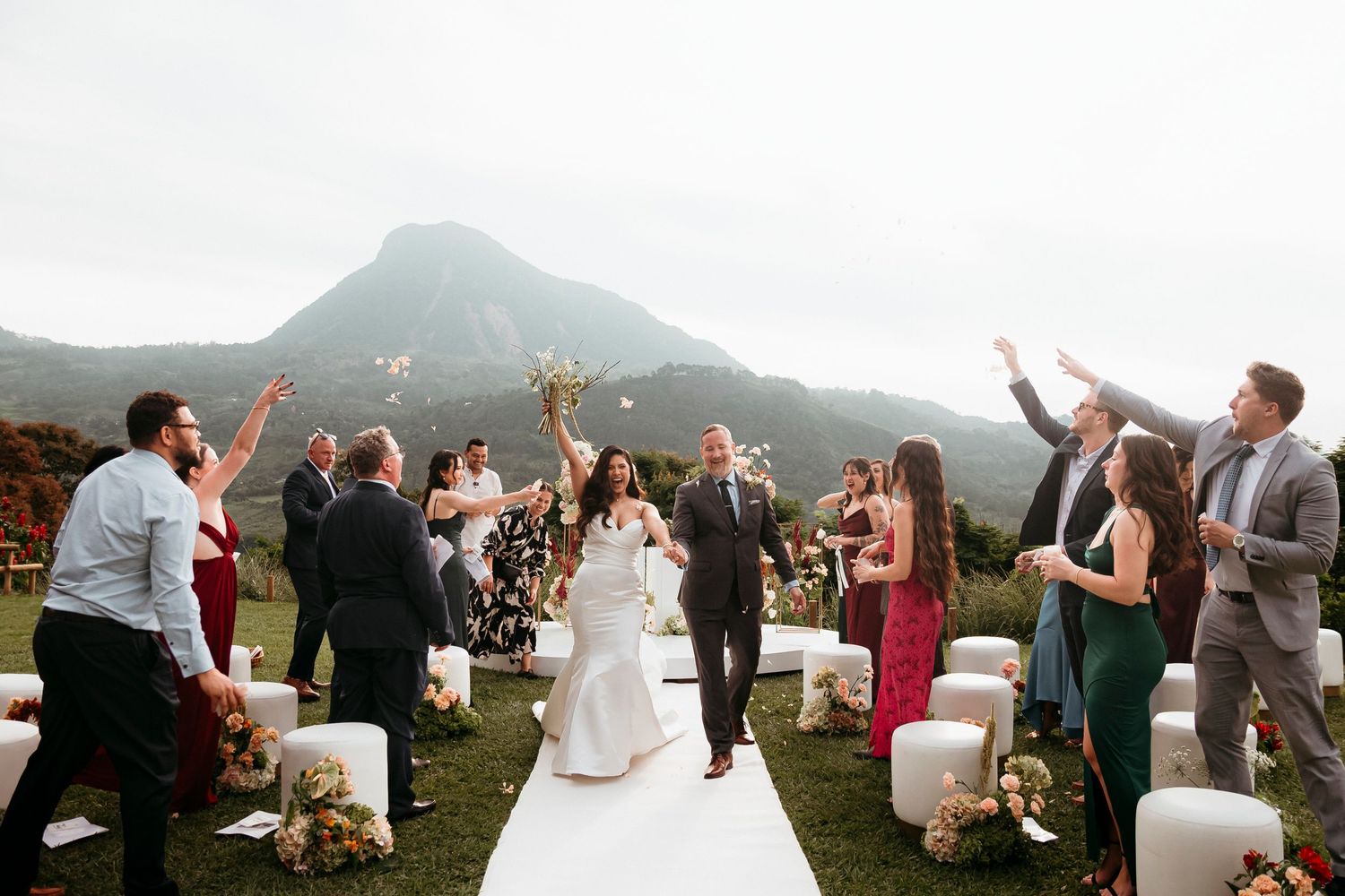 Wedding guests celebrate on an outdoor aisle with mountain views in the background.