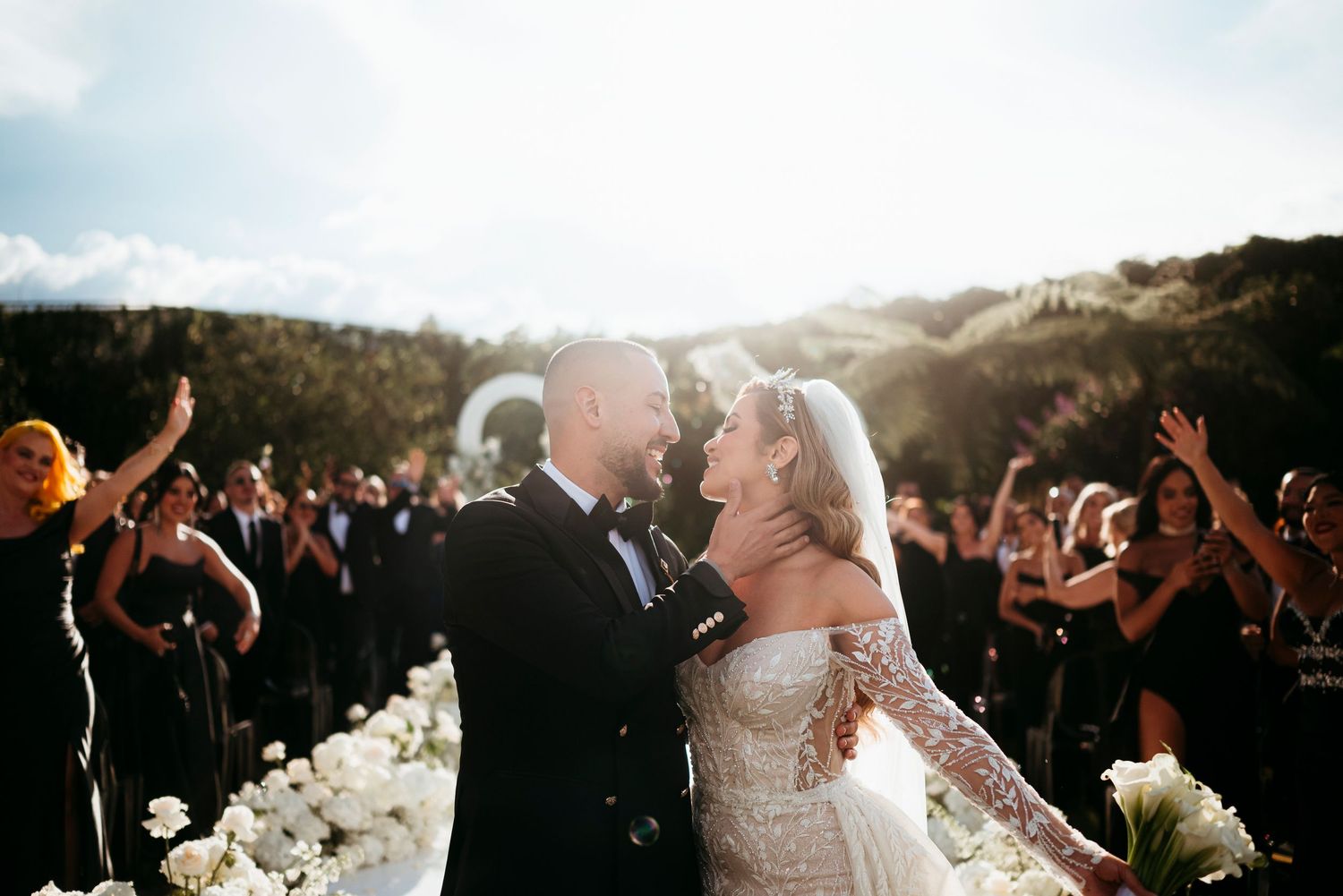 Wedding guests celebrate on the dance floor during sunset at an outdoor reception celebration.
