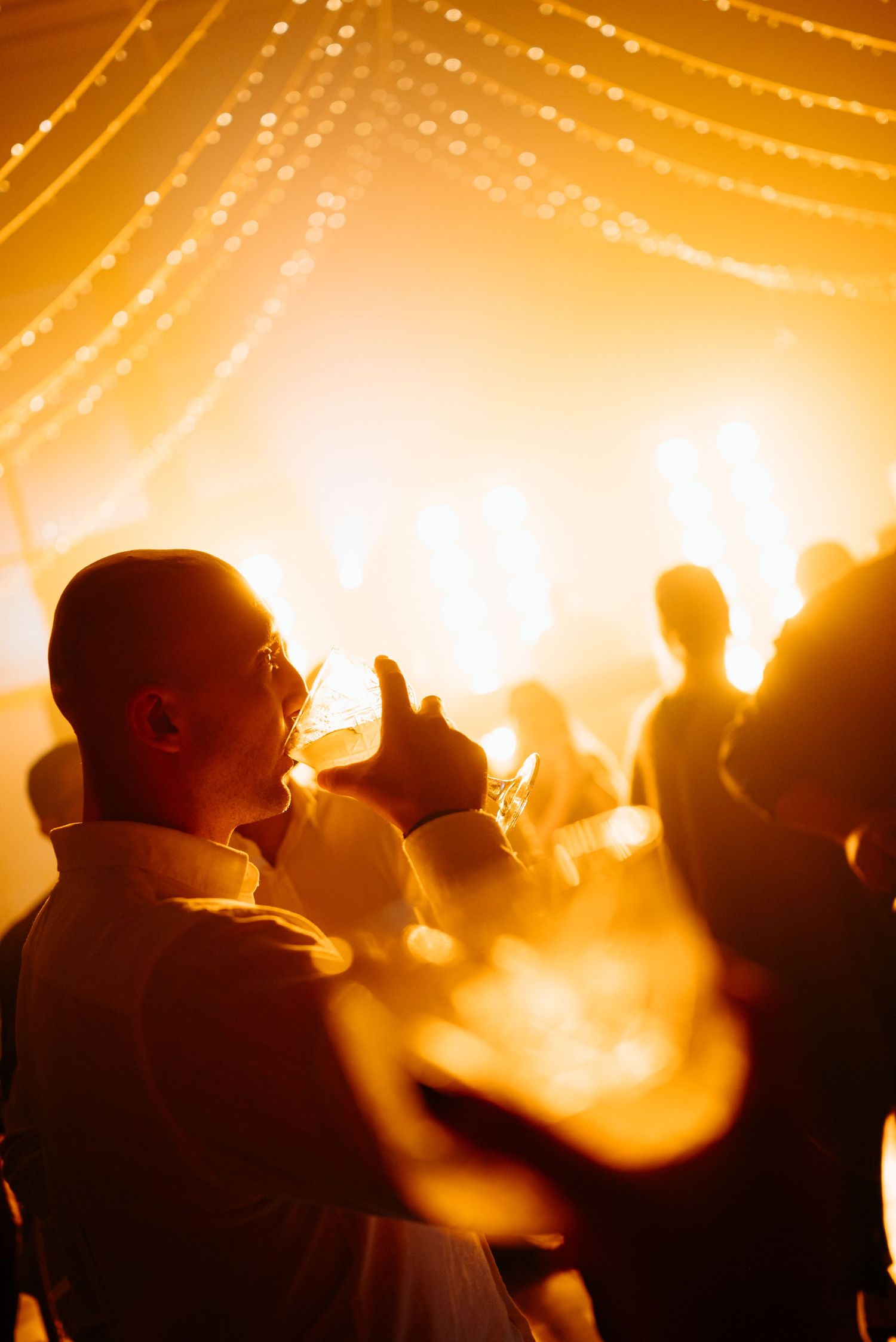 Silhouettes of concert crowd against bright orange stage lights creating a warm atmospheric glow.