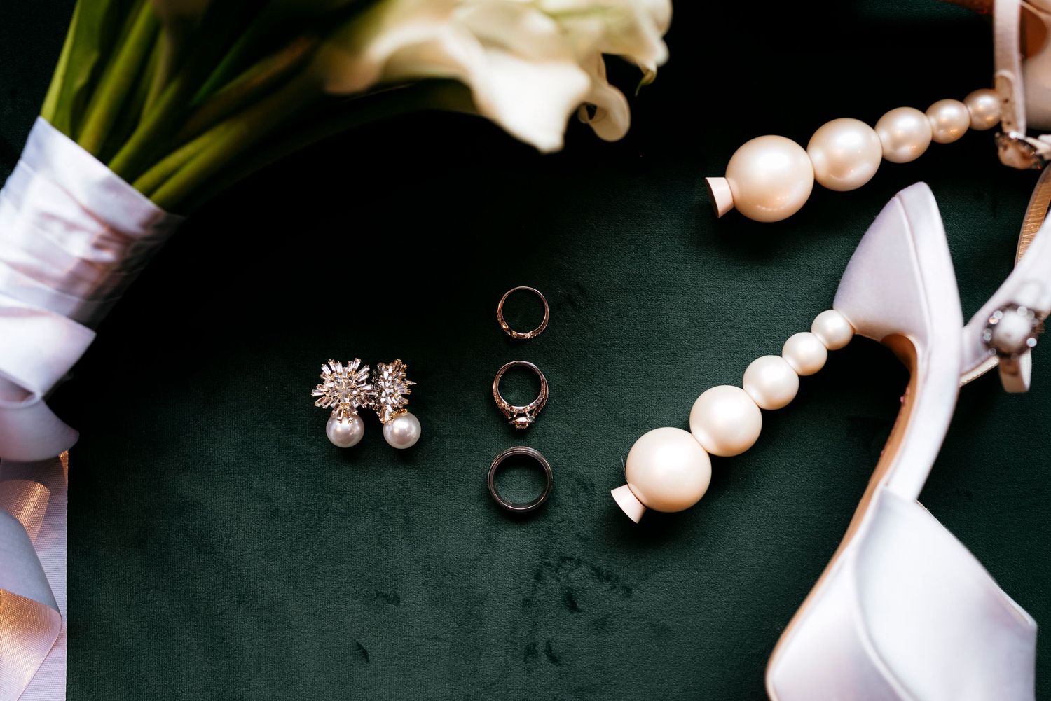 Delicate white pearl necklace with matching earrings arranged on dark background with soft lighting.