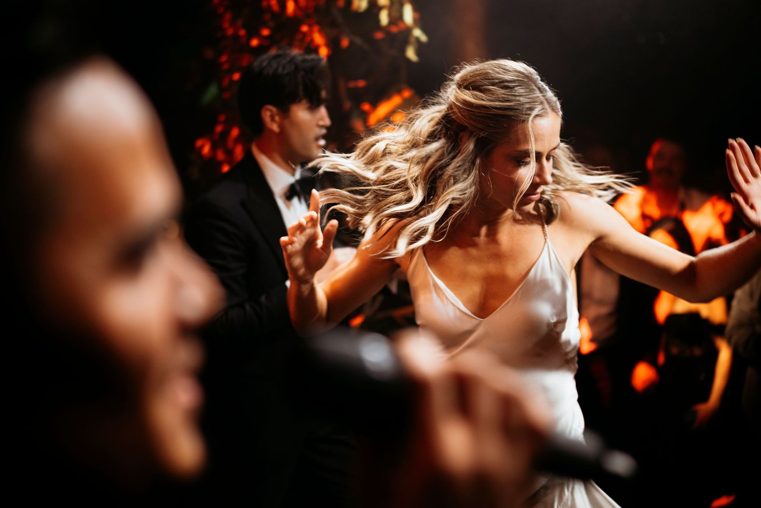 A dynamic dance floor moment at a wedding with flowing hair and motion captured in warm lighting.