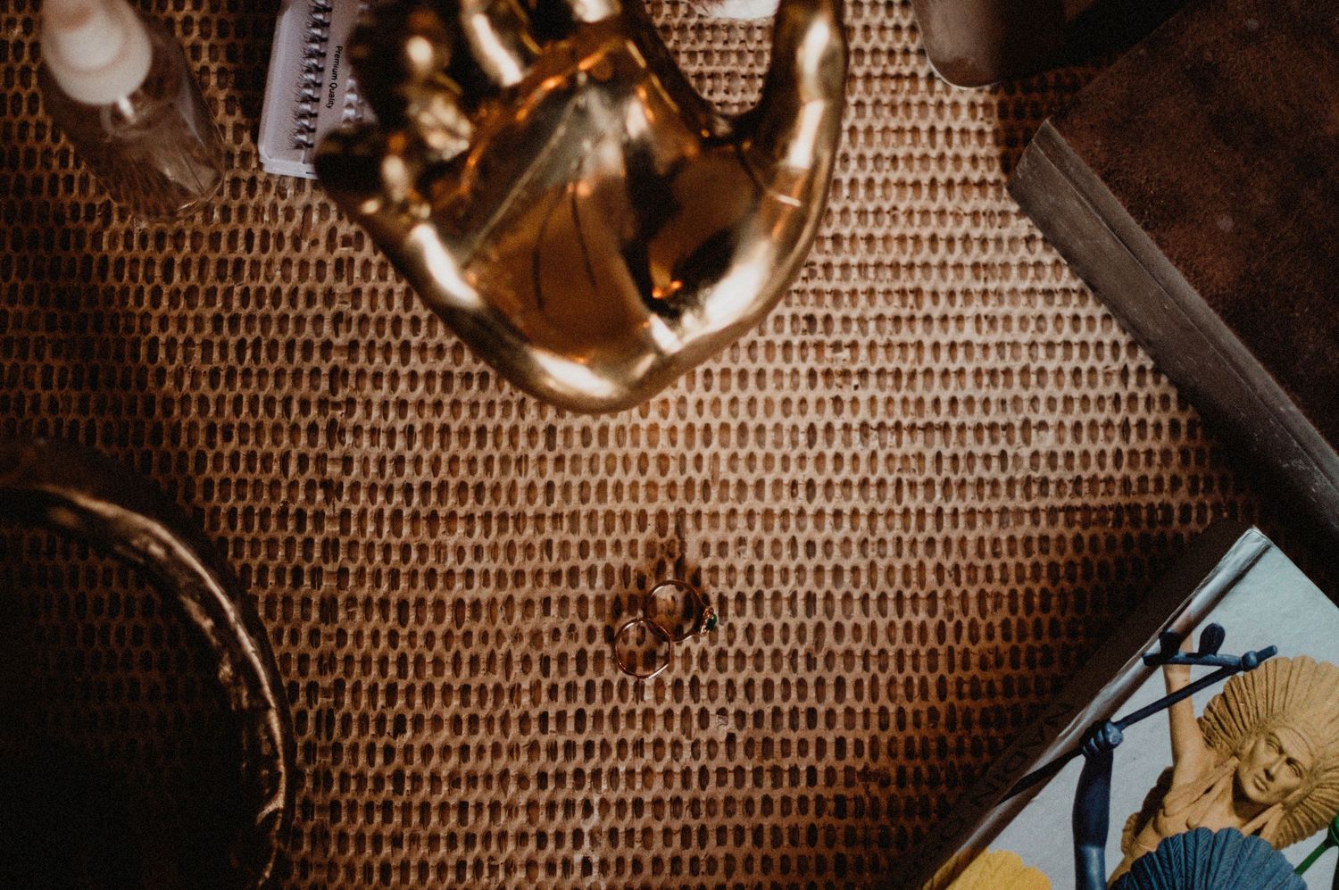 Glass of whiskey and playing cards on a textured brown surface with dramatic lighting casting warm shadows.