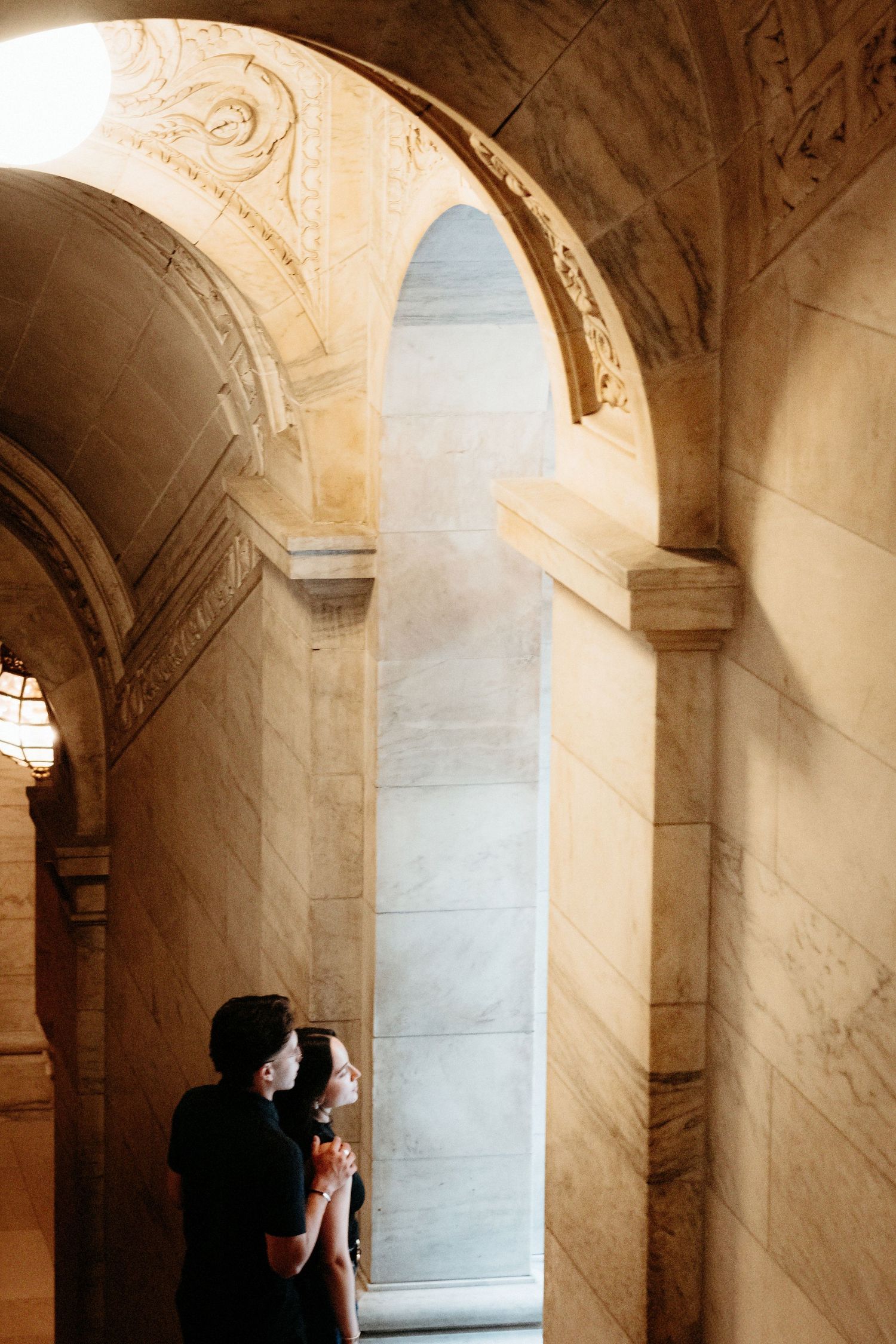 A silhouette of a couple in a grand architectural archway with ornate stone detailing.