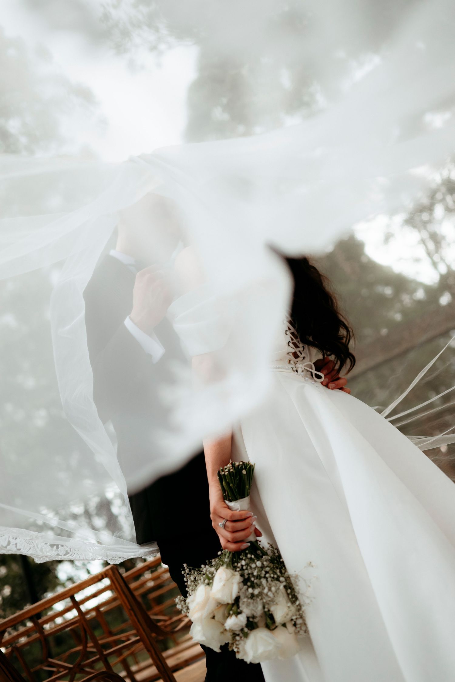 A flowing white wedding dress billows in the wind creating an ethereal and romantic outdoor scene.
