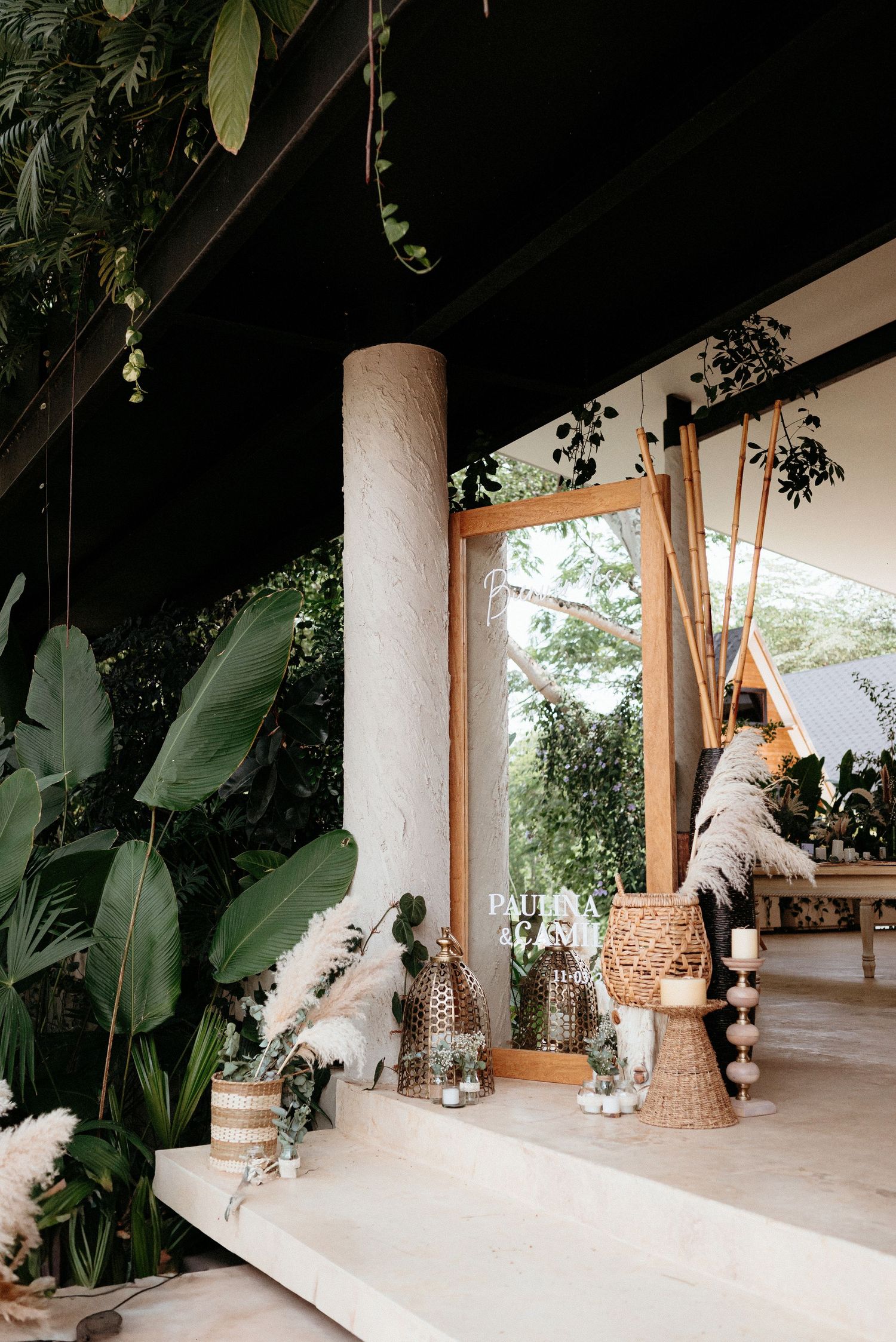 Bohemian veranda with white column, hanging plants, and woven furniture creating a cozy tropical outdoor living space.