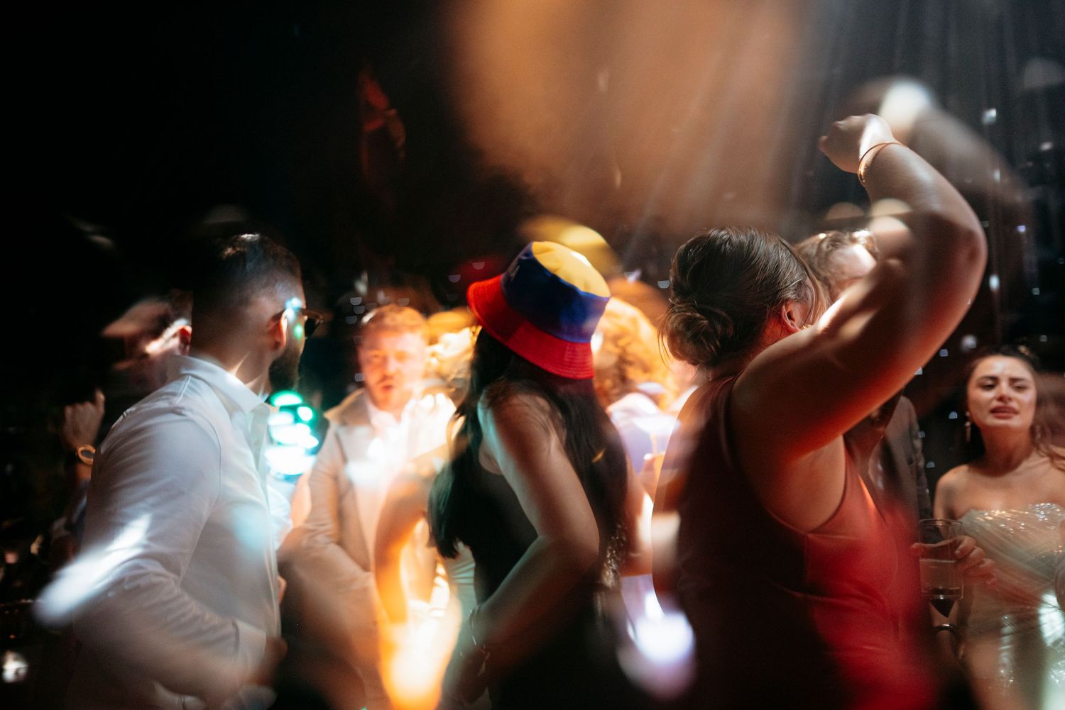 Energetic wedding reception dance floor with guests celebrating under dramatic lighting.