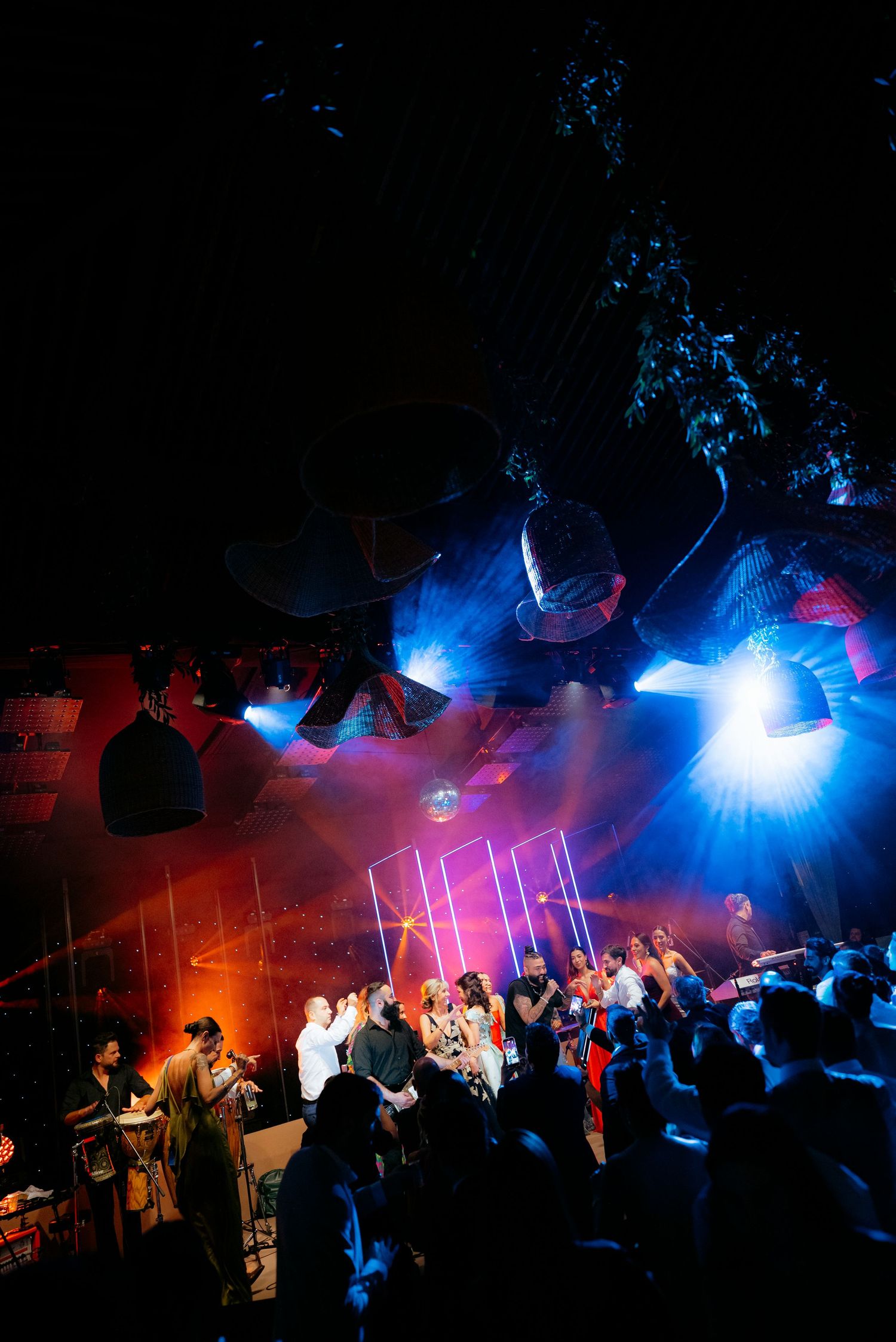 Energetic wedding reception dance floor with vibrant blue and orange stage lights illuminating a crowd of guests.