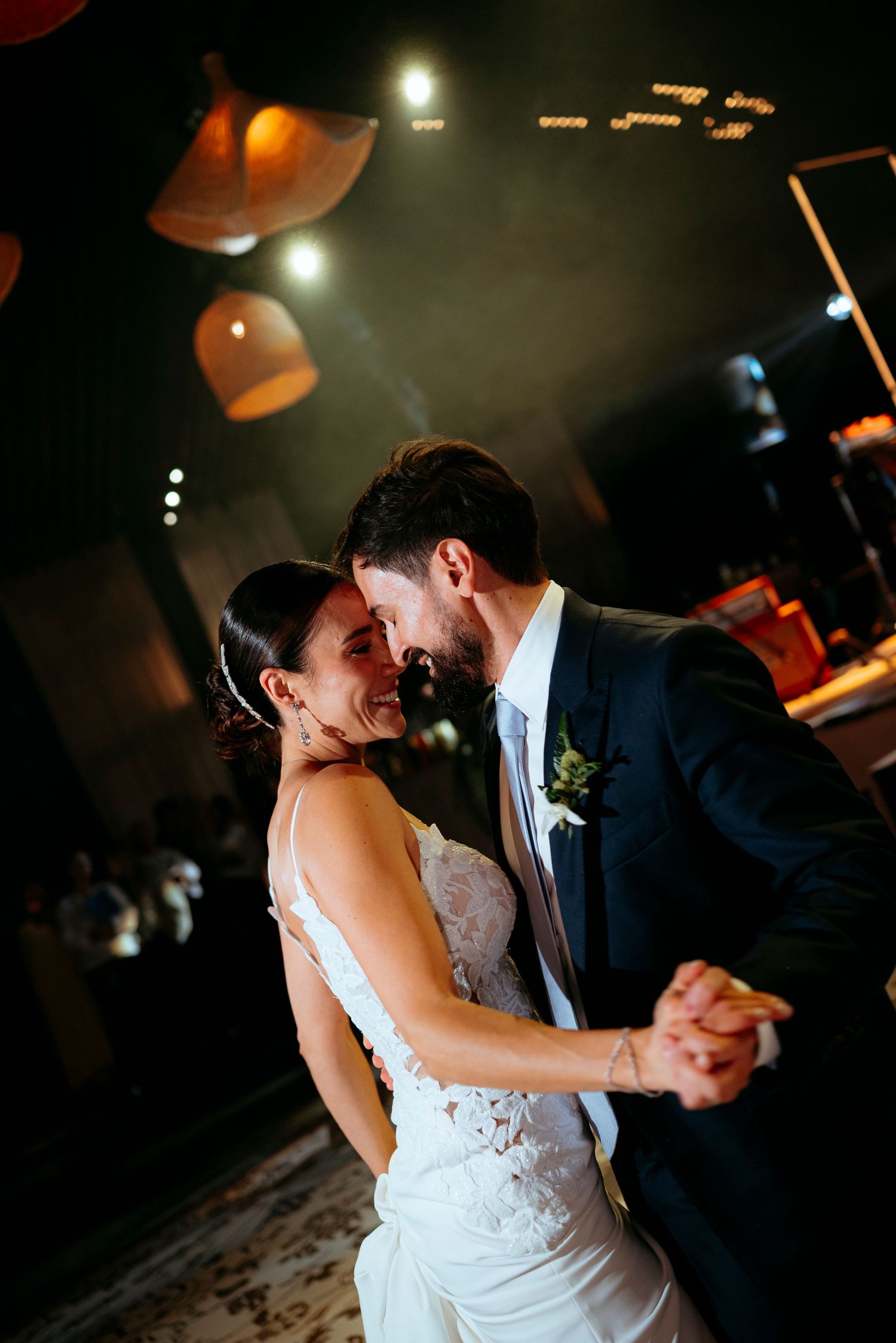 Romantic first dance as newlyweds share intimate moment under warm lights at wedding reception.