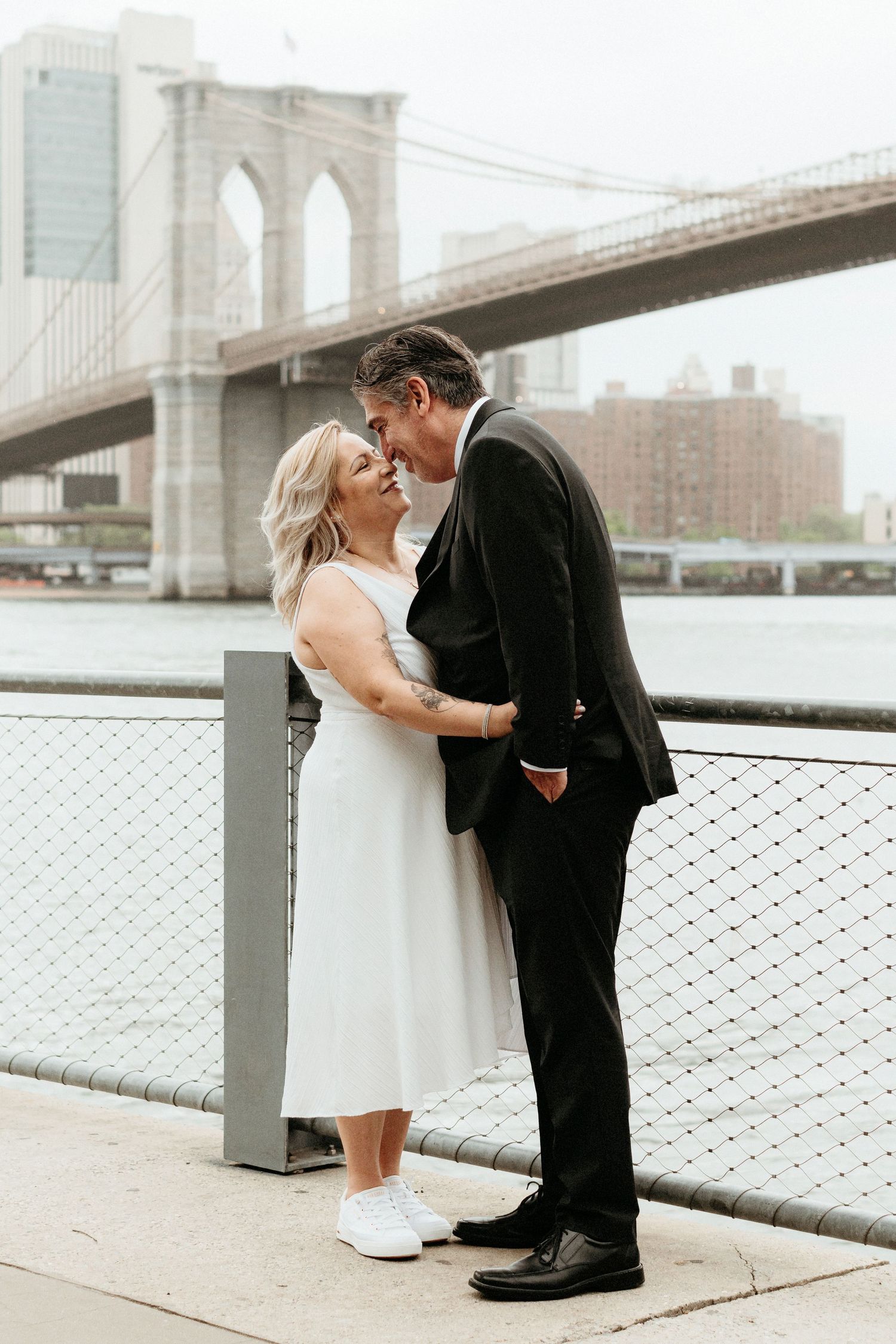 A romantic couple shares an intimate moment near the Brooklyn Bridge.
