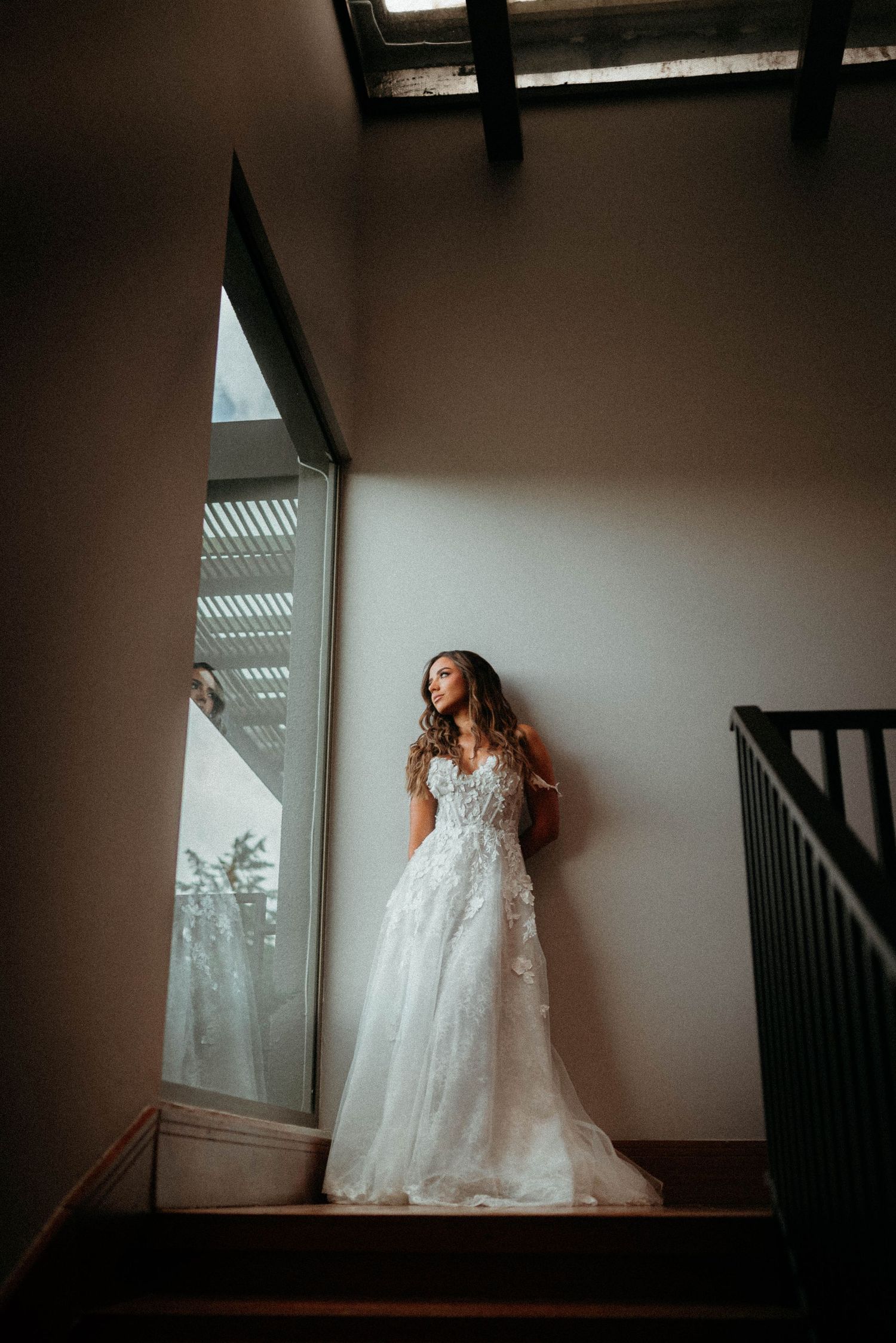 Artistic sequence of a bride in a flowing white lace gown posing against a wall in dramatic lighting and shadows.