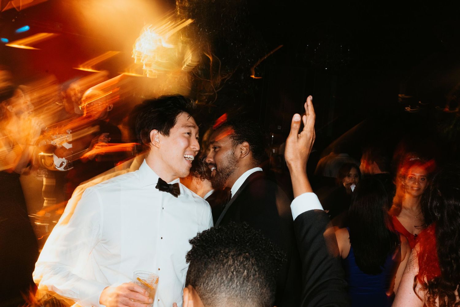 A lively wedding reception scene with guests dancing and celebrating under warm lighting.