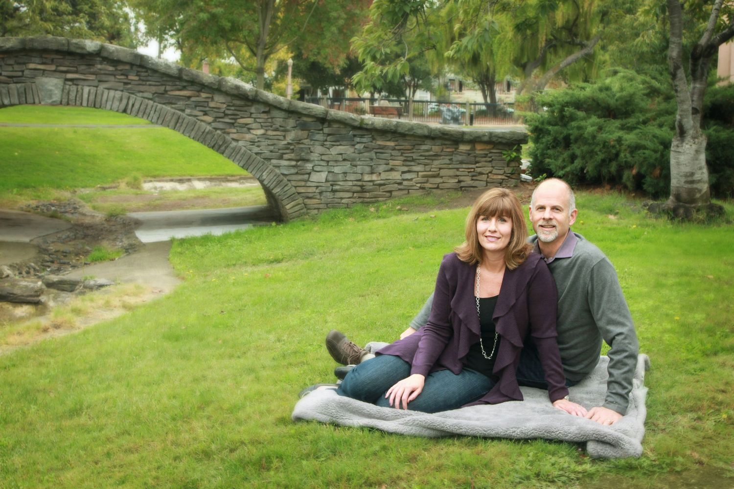 Couple in a park with a bridge and a weeping willow tree