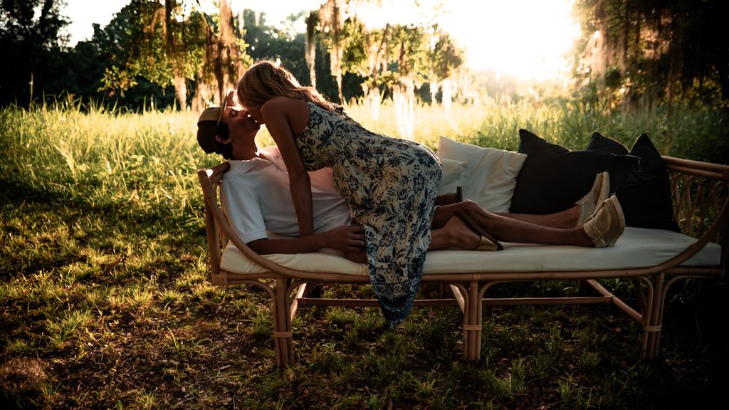 A couple lounges together on a blanket in a sunlit meadow during a romantic golden hour picnic.
