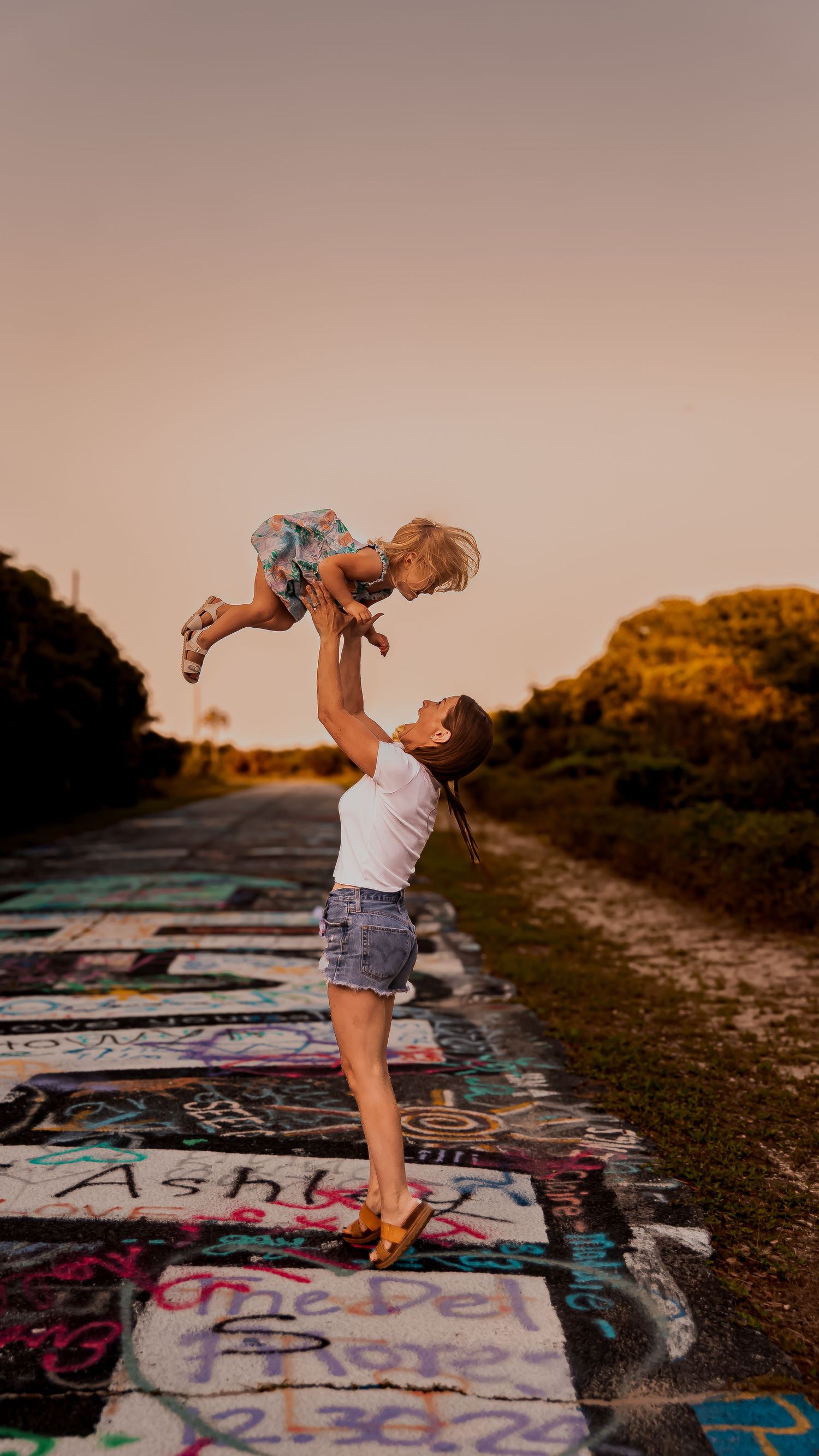 A series of photos showing playful interaction between parent and child on graffiti-covered concrete at sunset.
