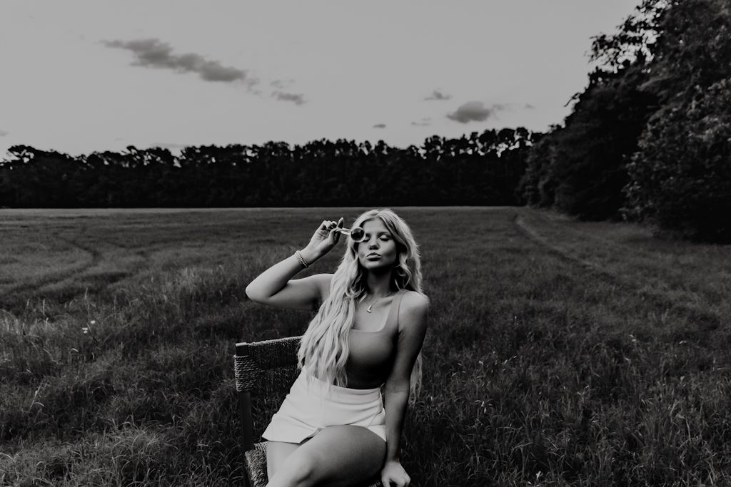 A black and white photo series shows someone in a field at sunset posing in different positions.