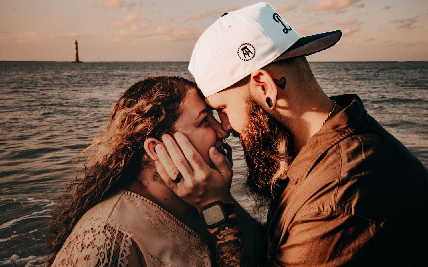A couple shares an intimate kiss on the beach during sunset in a series of romantic photos.