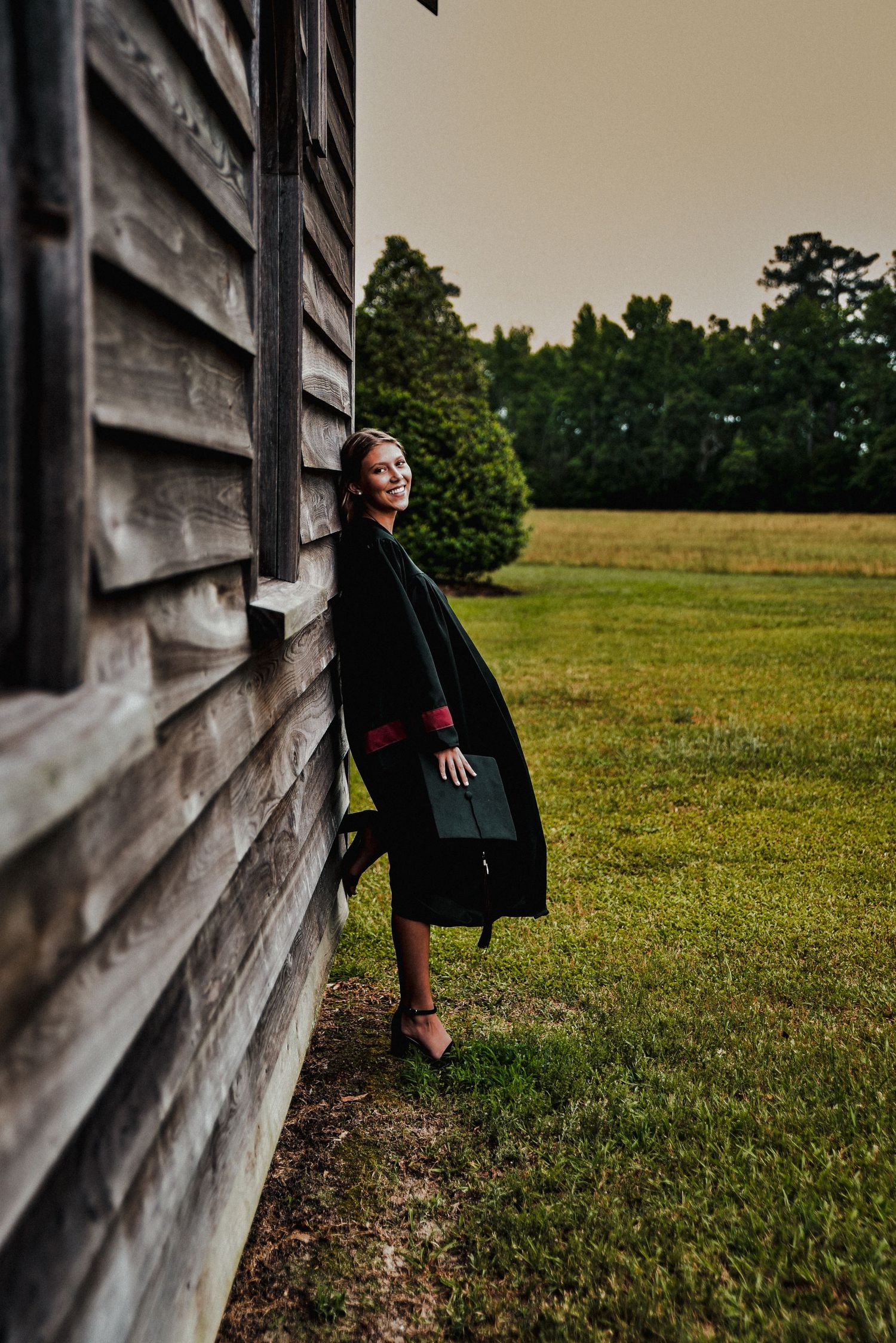 A series of three photos showing someone leaning against a rustic wooden wall beside a grassy field at dusk.