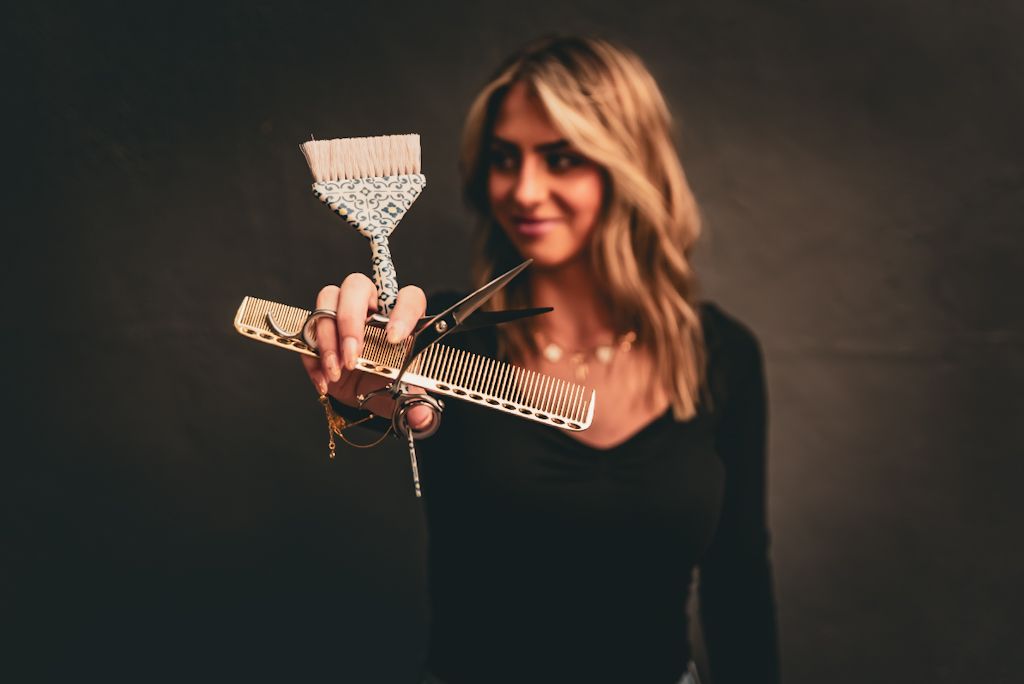 A hand holding a martini glass filled with a clear cocktail garnished with a lemon twist against a dark background.