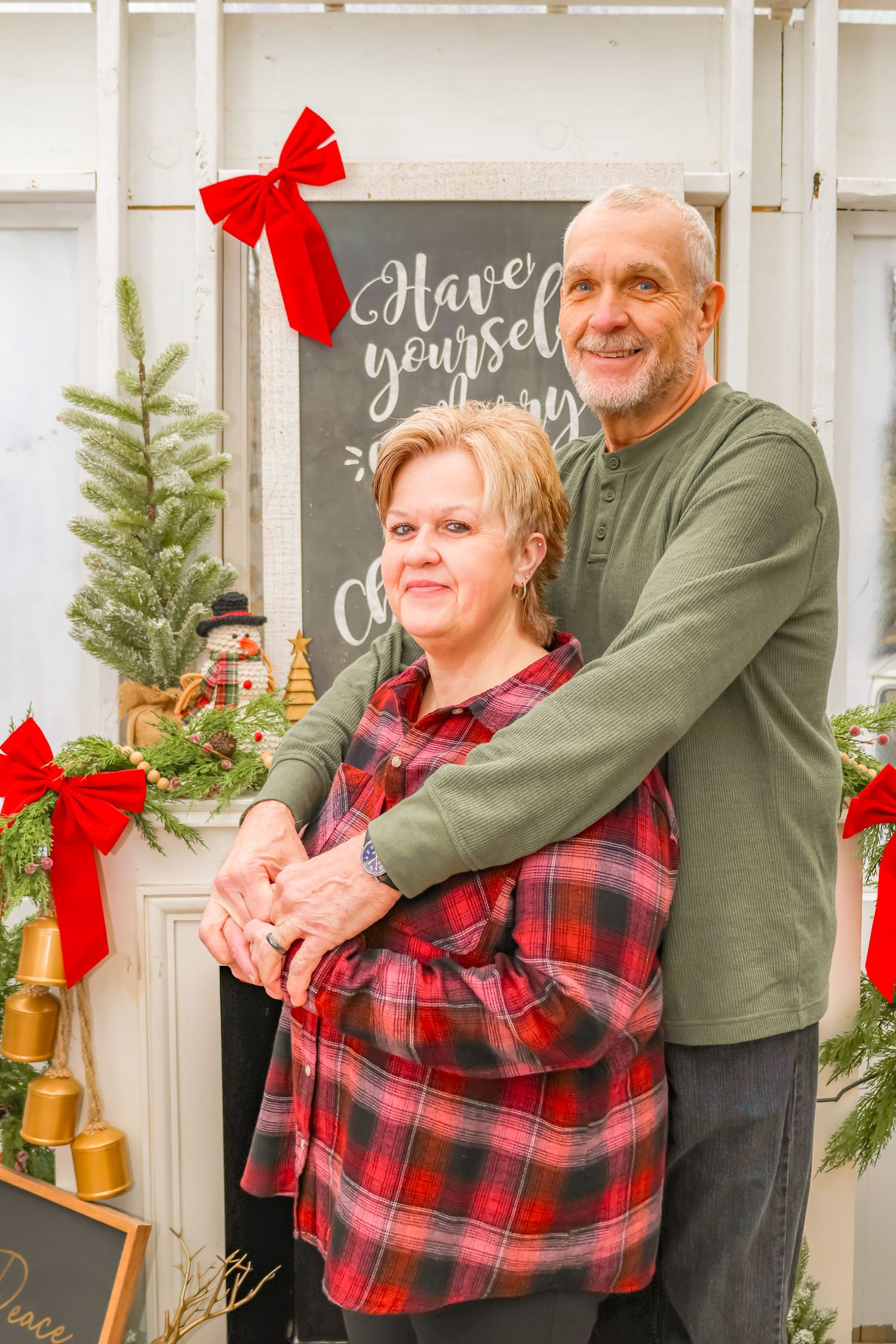 Festive holiday portrait with Christmas decorations and chalkboard sign in background.