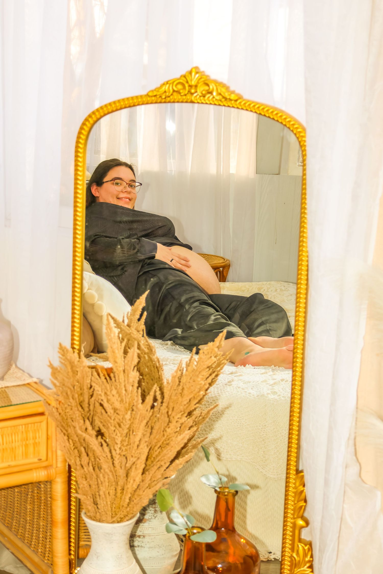 Mirror reflection showing relaxed figure reclining on couch with decorative pampas grass.