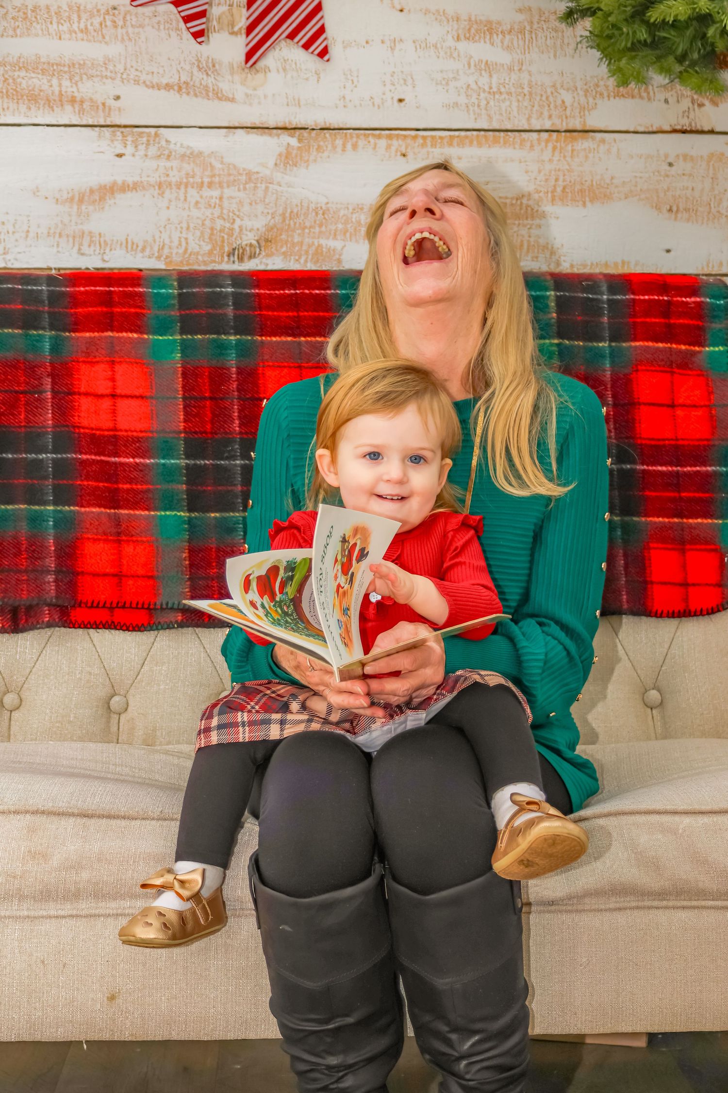 Joyful holiday moment on a plaid-covered couch while reading a Christmas story book.