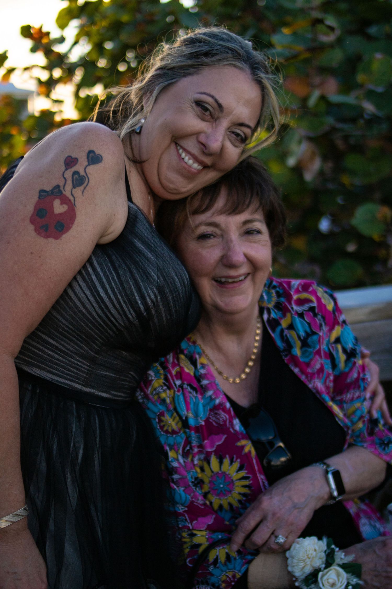Two guests in evening attire share a joyful moment at an outdoor celebration.