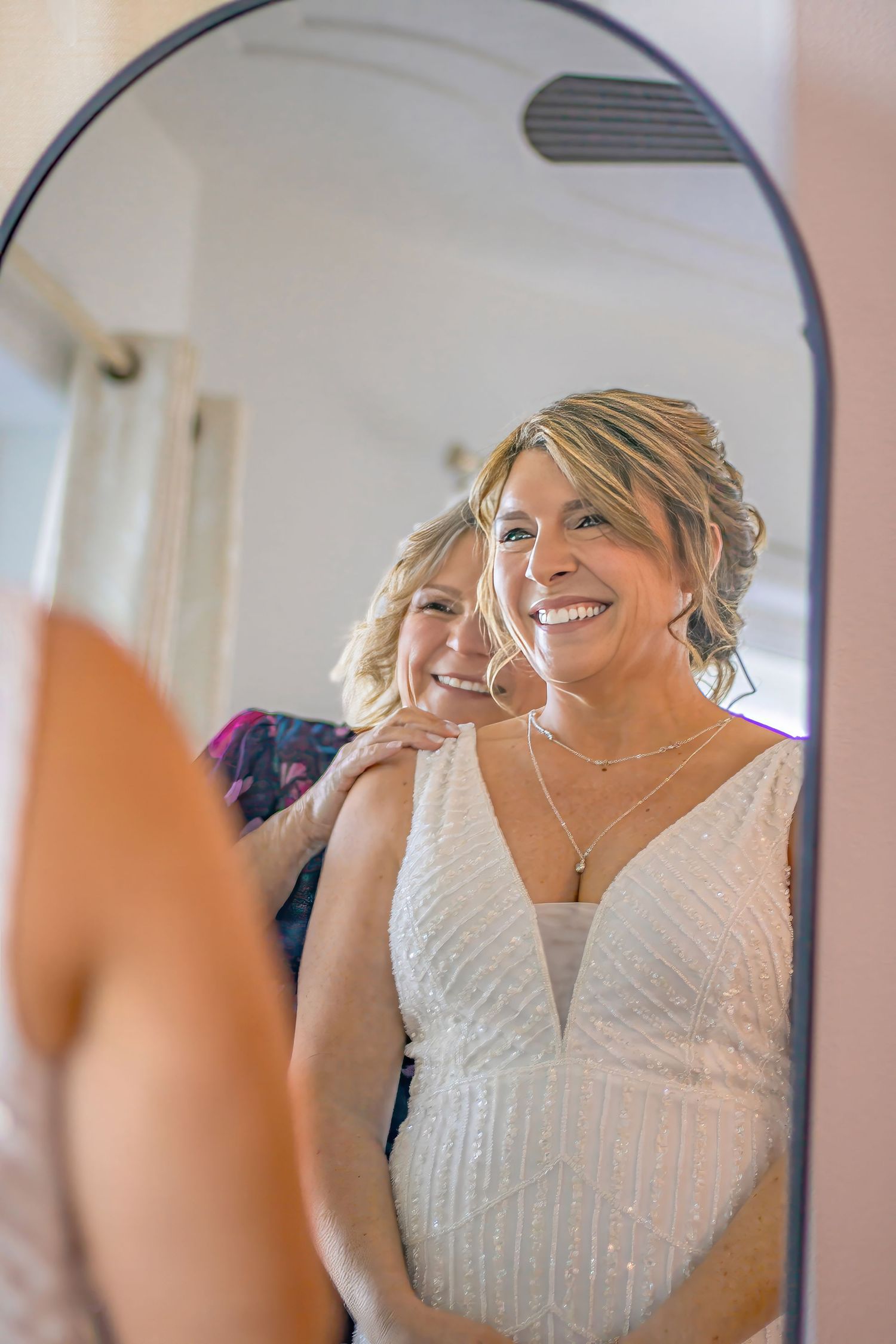 A sequence of bridal portraits showing a person in a white beaded wedding dress looking into a mirror with joyful expressions.