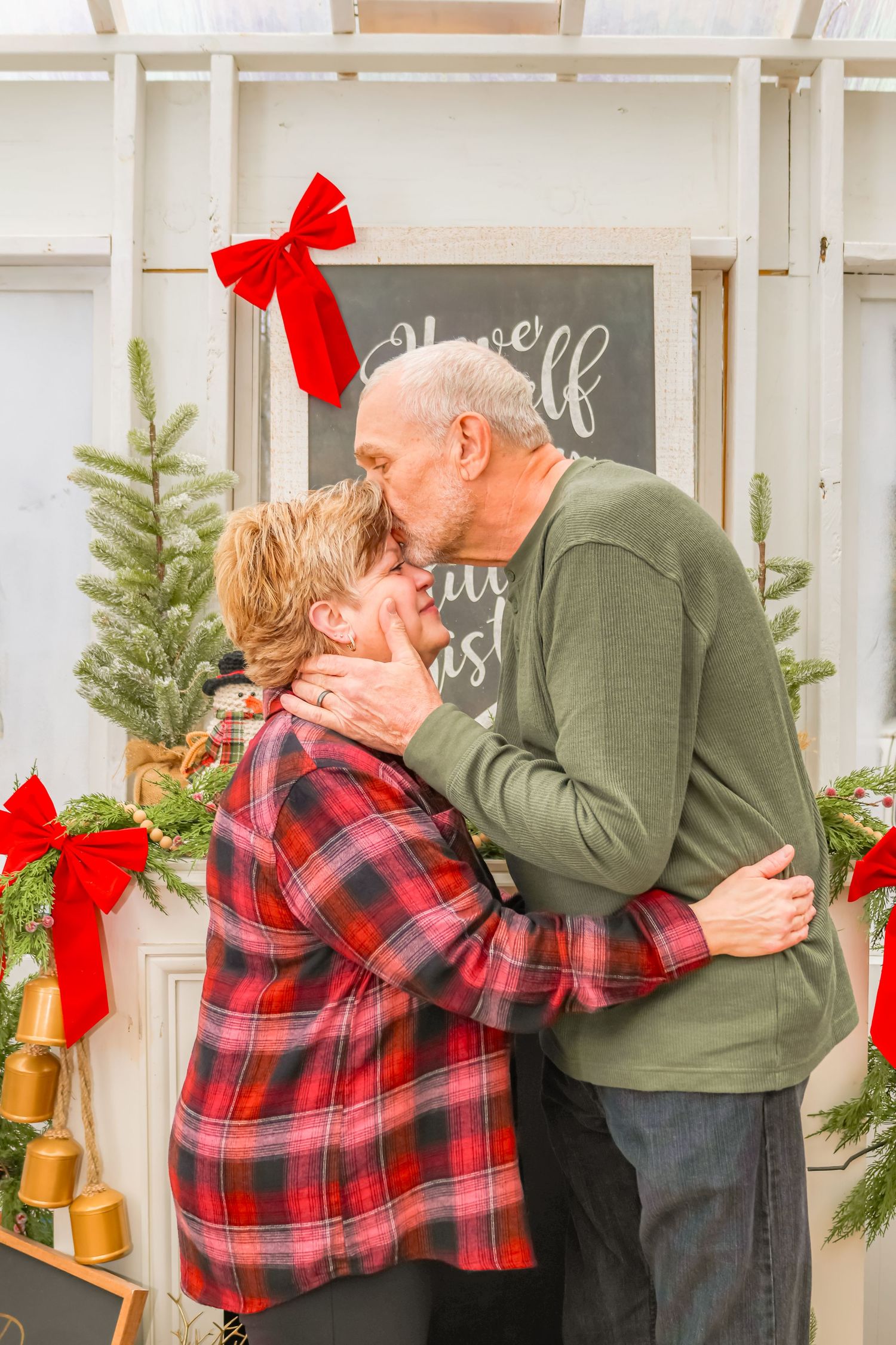 Intimate holiday moment captured in front of chalkboard sign with Christmas decorations.
