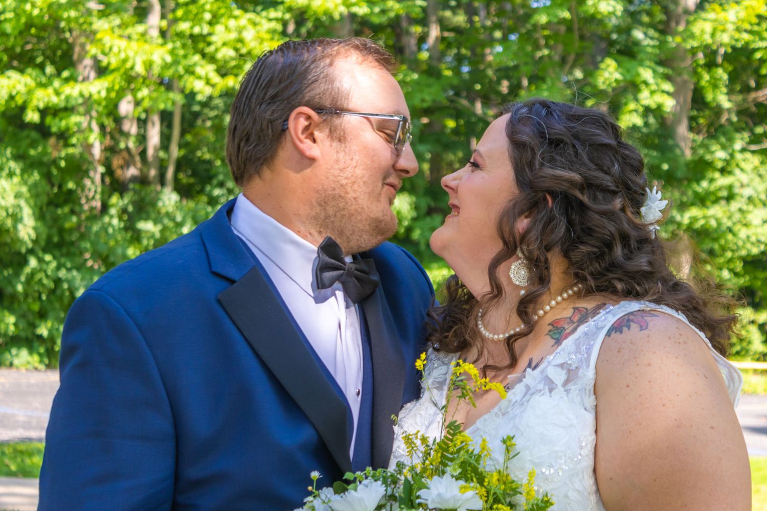 Wedding couple sharing a joyful moment outdoors with natural greenery backdrop.