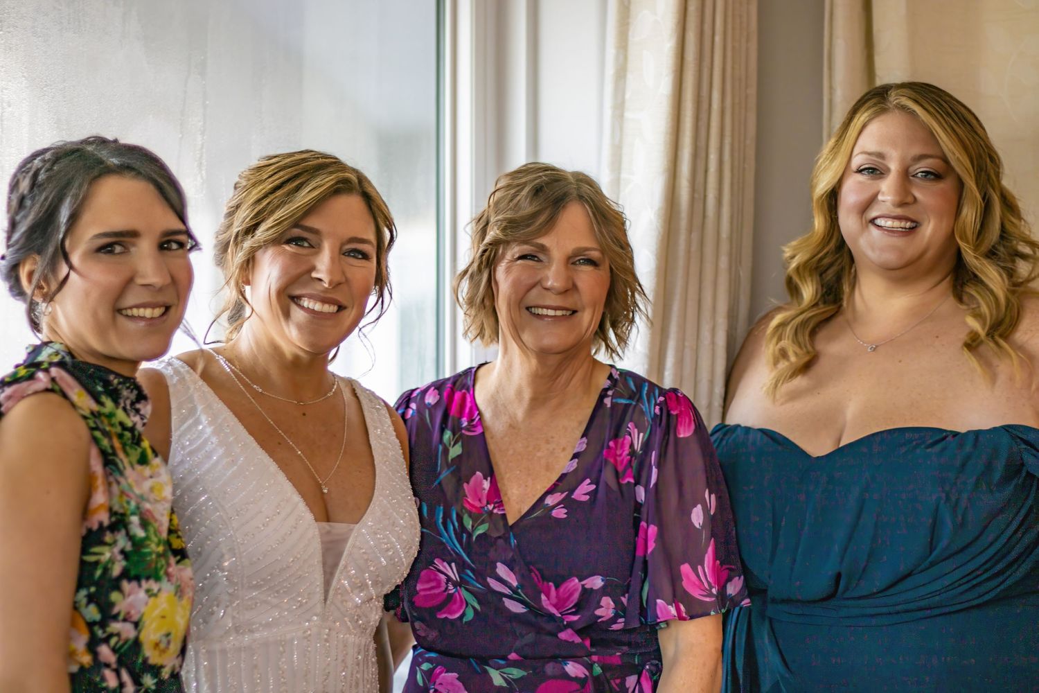 A group wearing colorful dresses poses together at a wedding celebration.