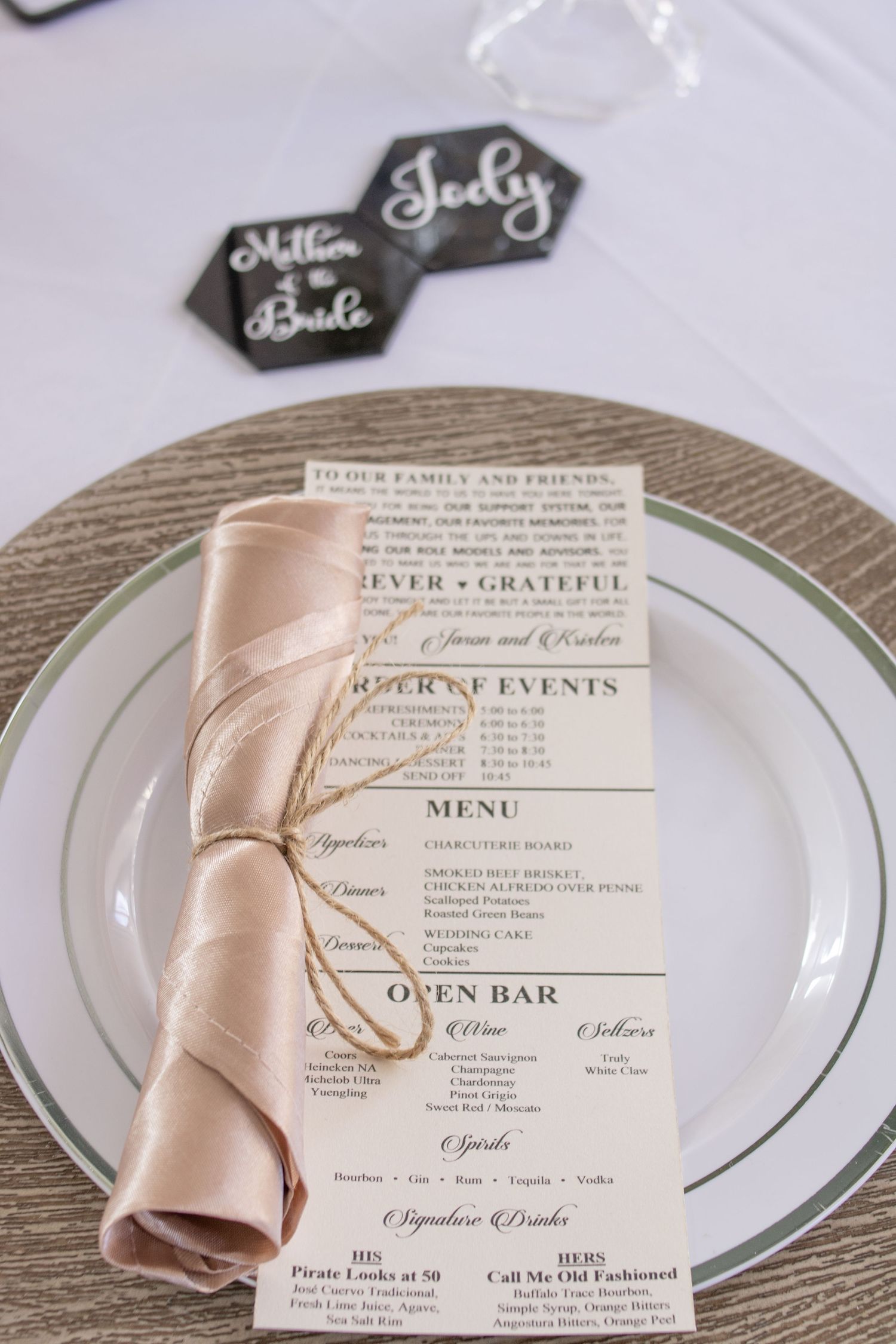 Wedding reception menu card with blush napkin on silver charger plate and hexagonal place cards.