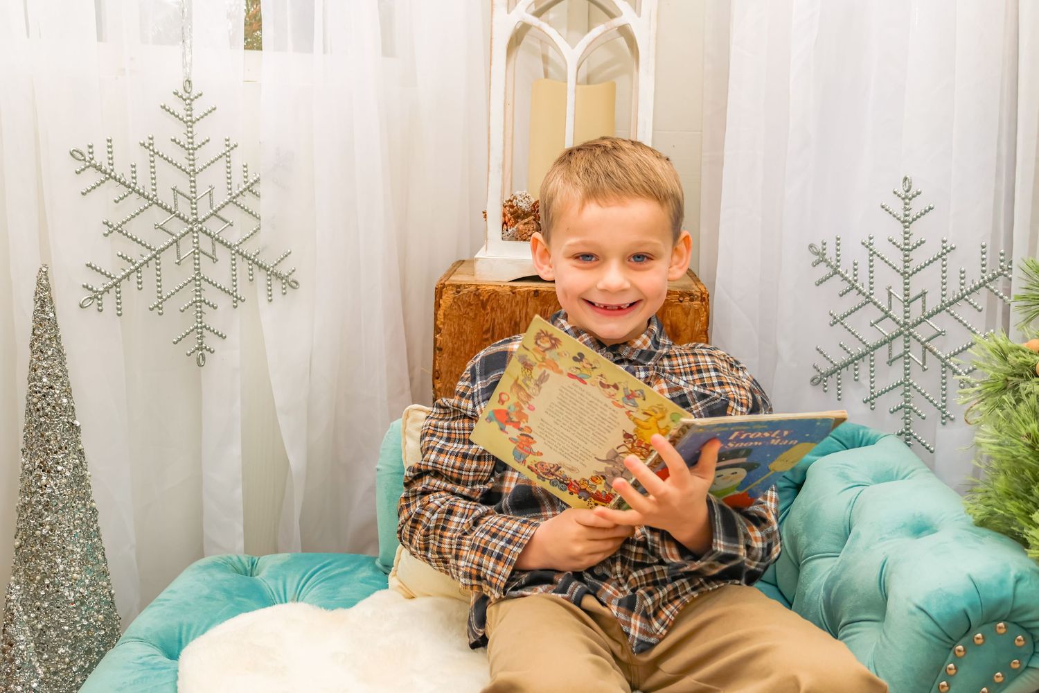 Young person sitting in a chair holding a gift with silver snowflake decorations in background.