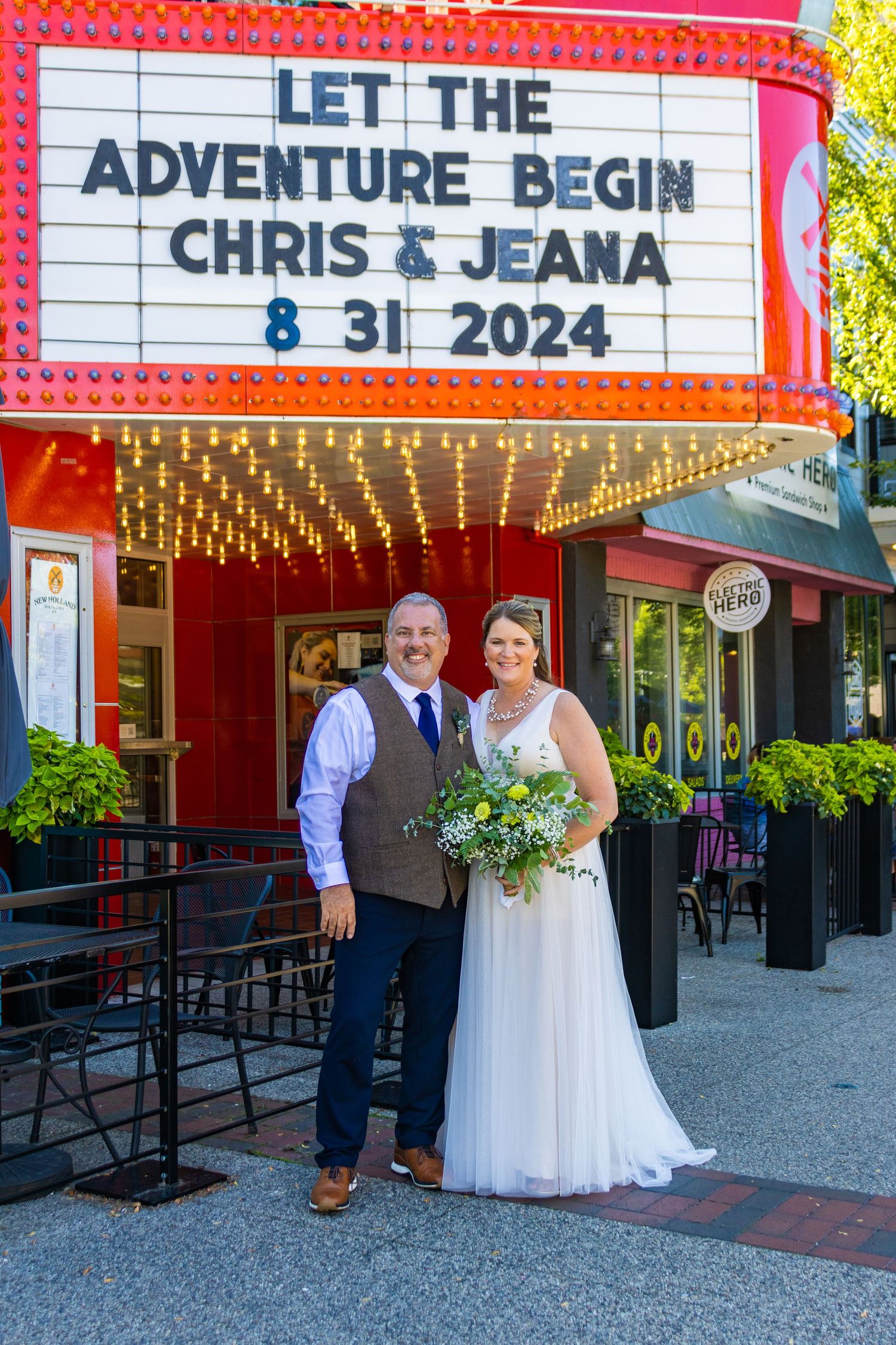 Wedding photo in front of vintage theater marquee with twinkle lights.
