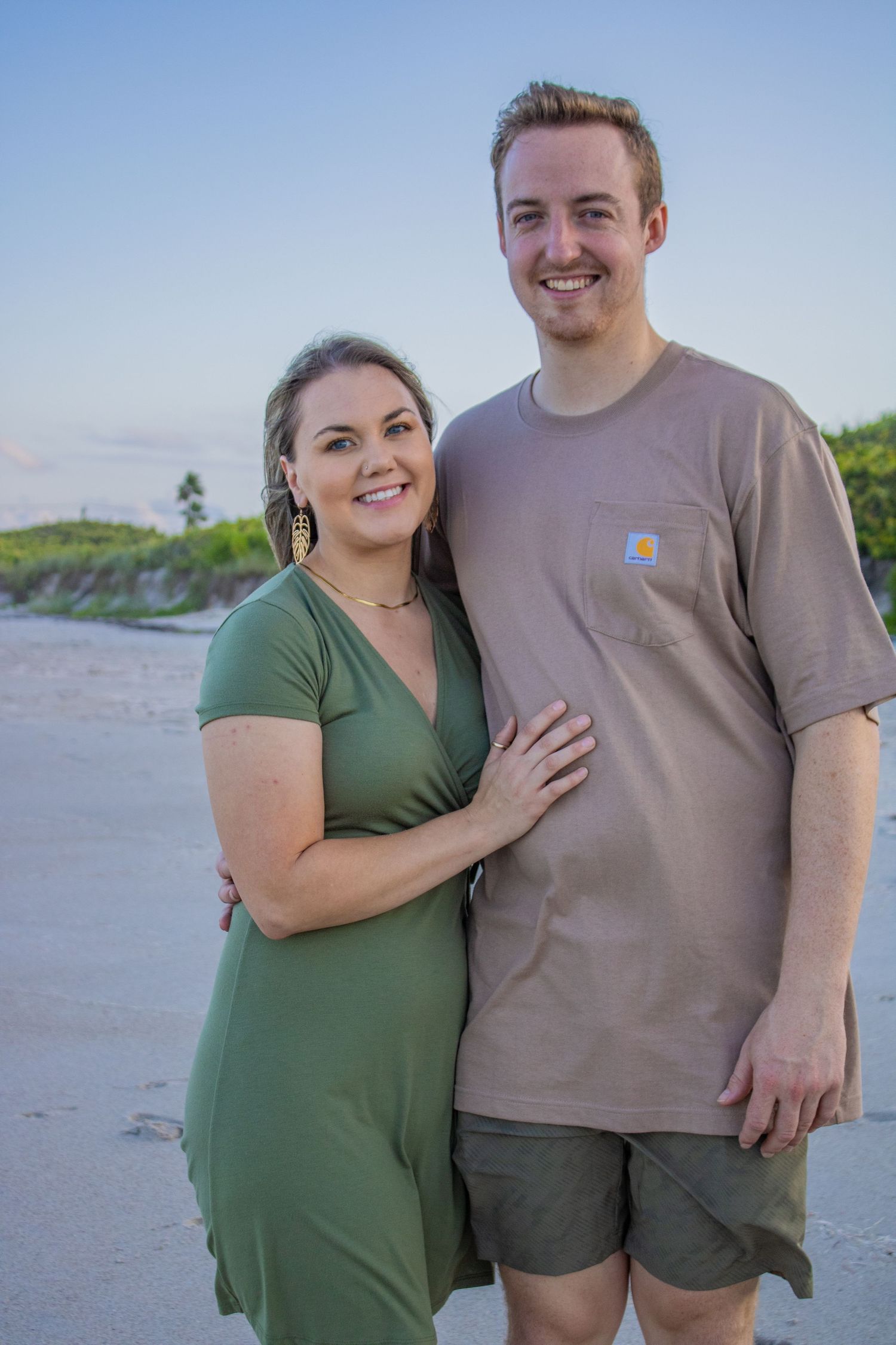 Couple posing casually on sandy beach during blue hour.