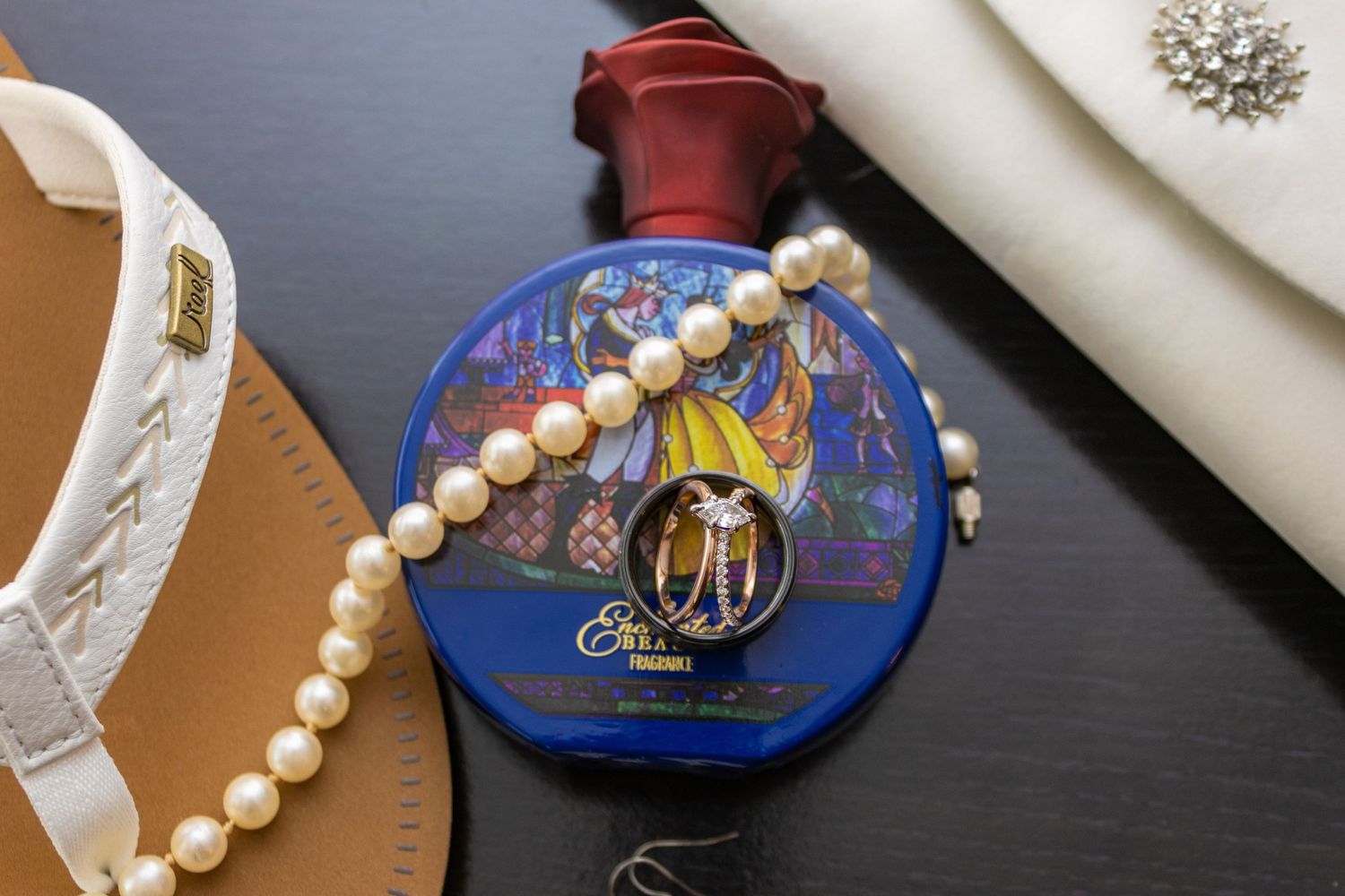 Wedding details including pearl jewelry and blue decorative box on dark surface.