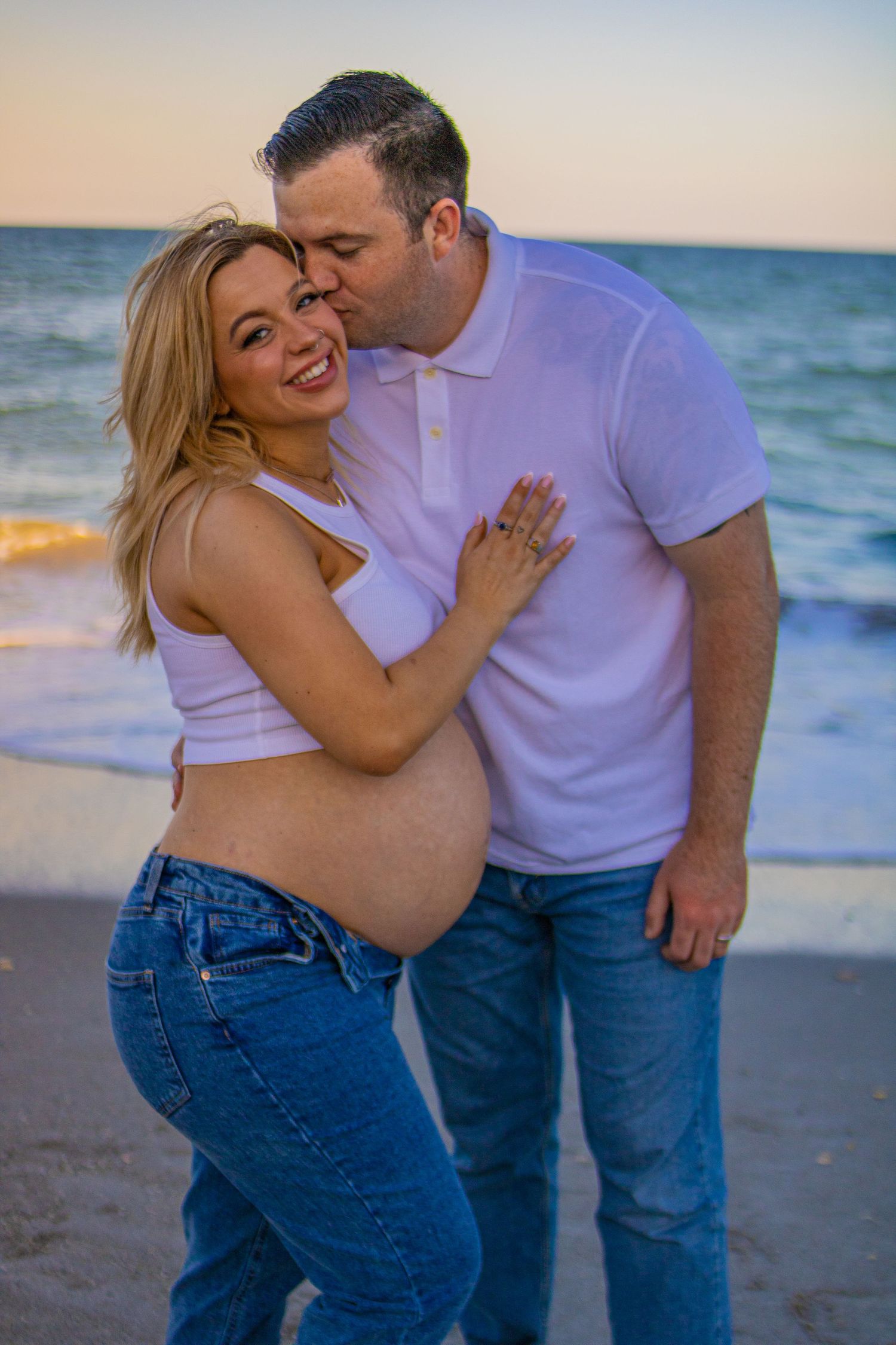 Intimate maternity beach photo of expecting couple during sunset.