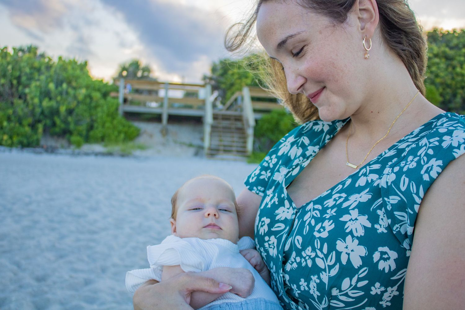 A tender moment shared between parent and baby on a sandy beach at sunset.