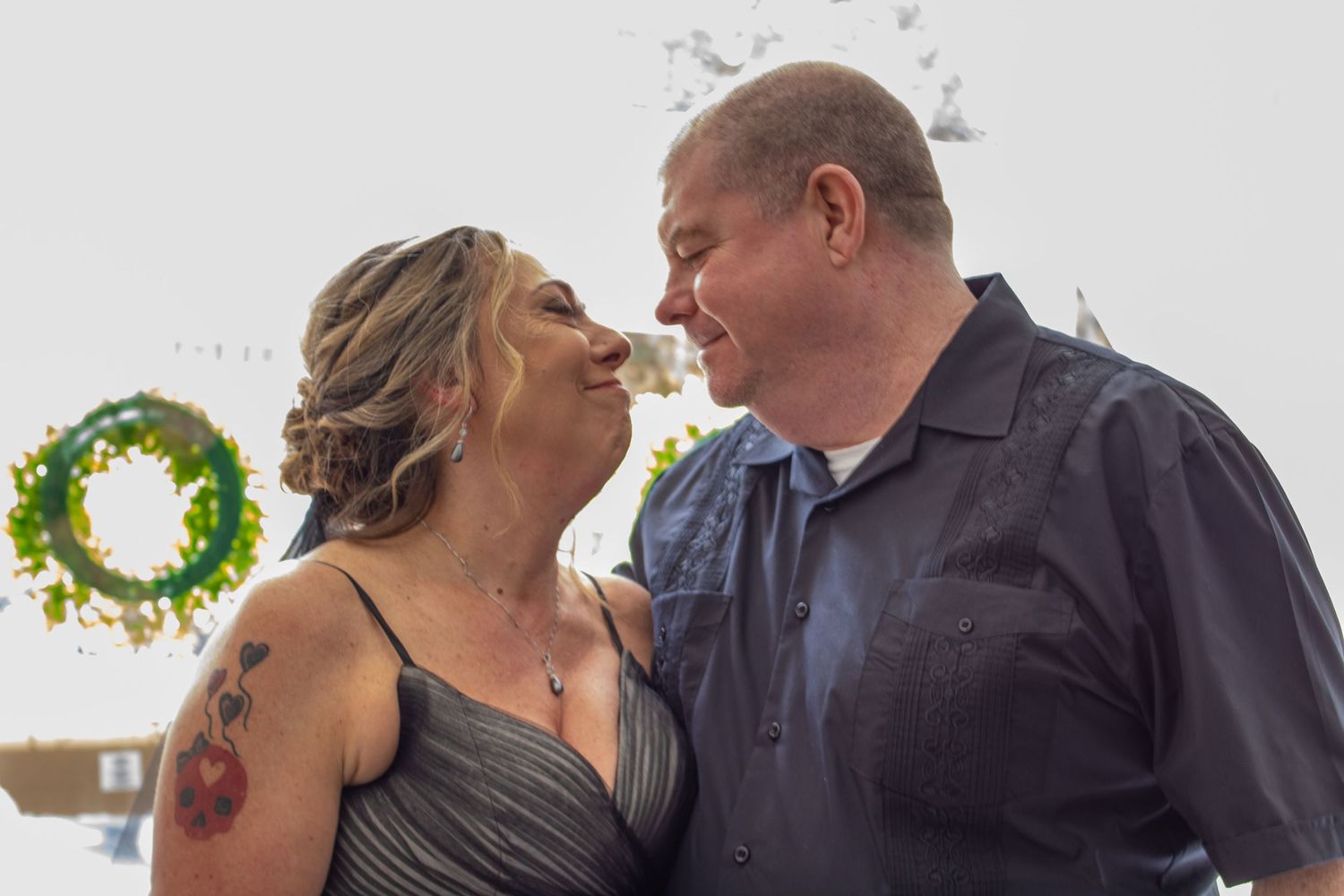 Intimate moment captured against green wreath backdrop at celebration.