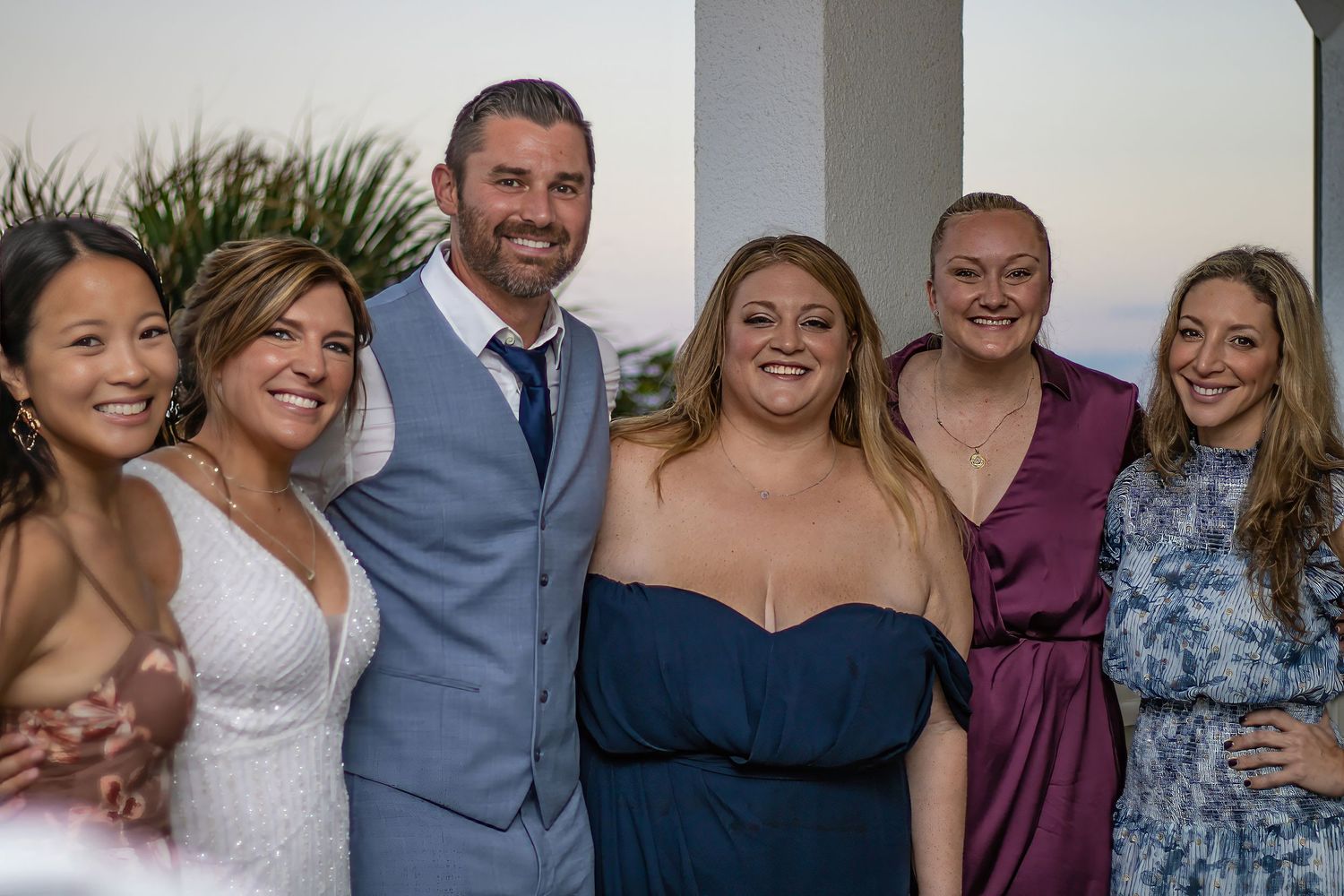Wedding party poses together for a group photo at sunset.