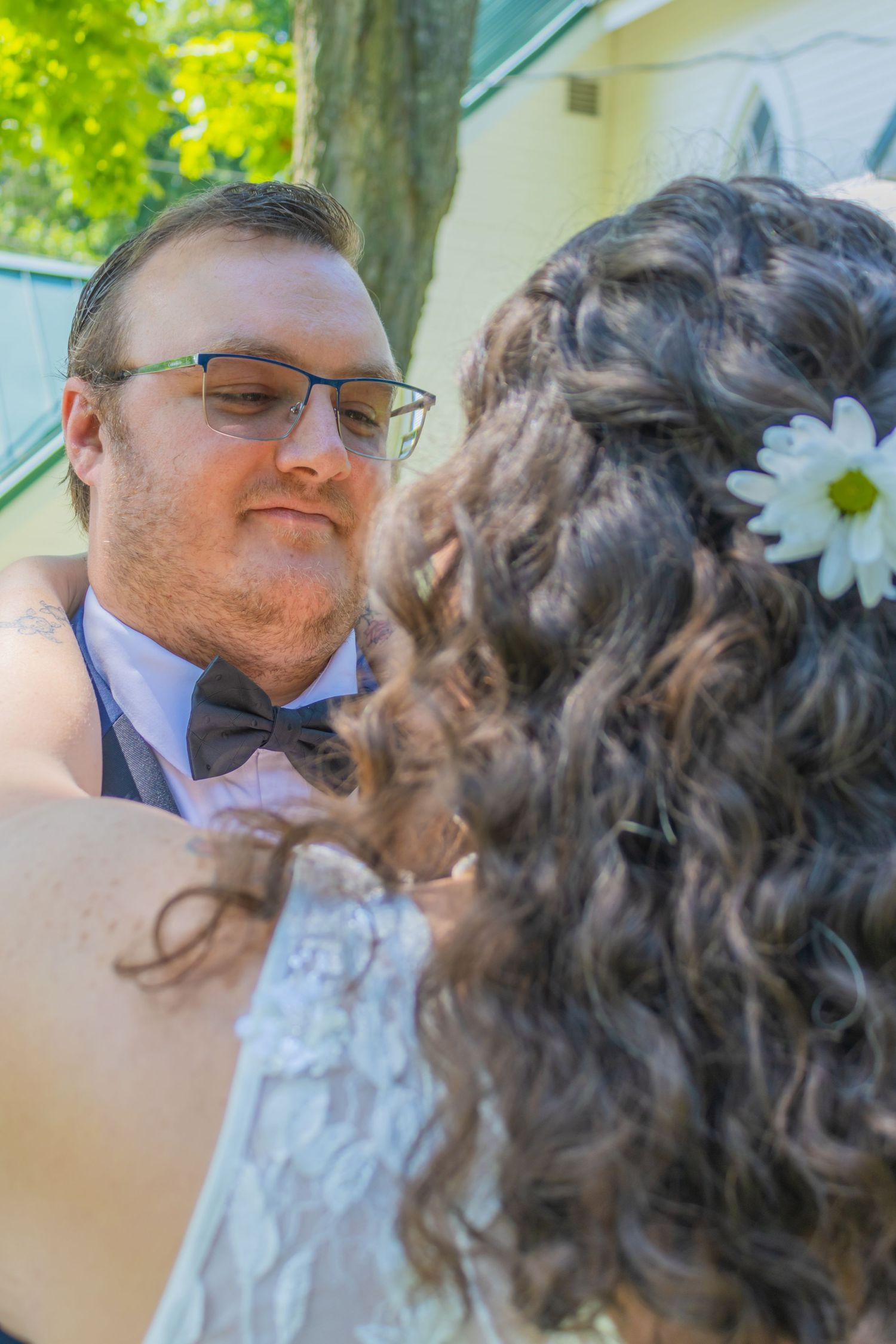 Wedding couple sharing an intimate moment outdoors with lush greenery in the background.