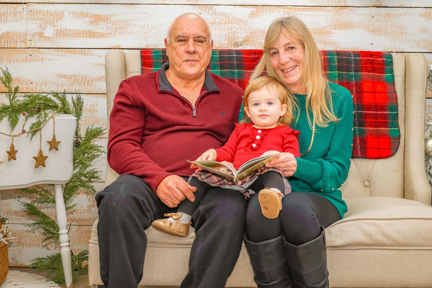 Cozy Christmas photo session on beige couch with story book and festive decor.