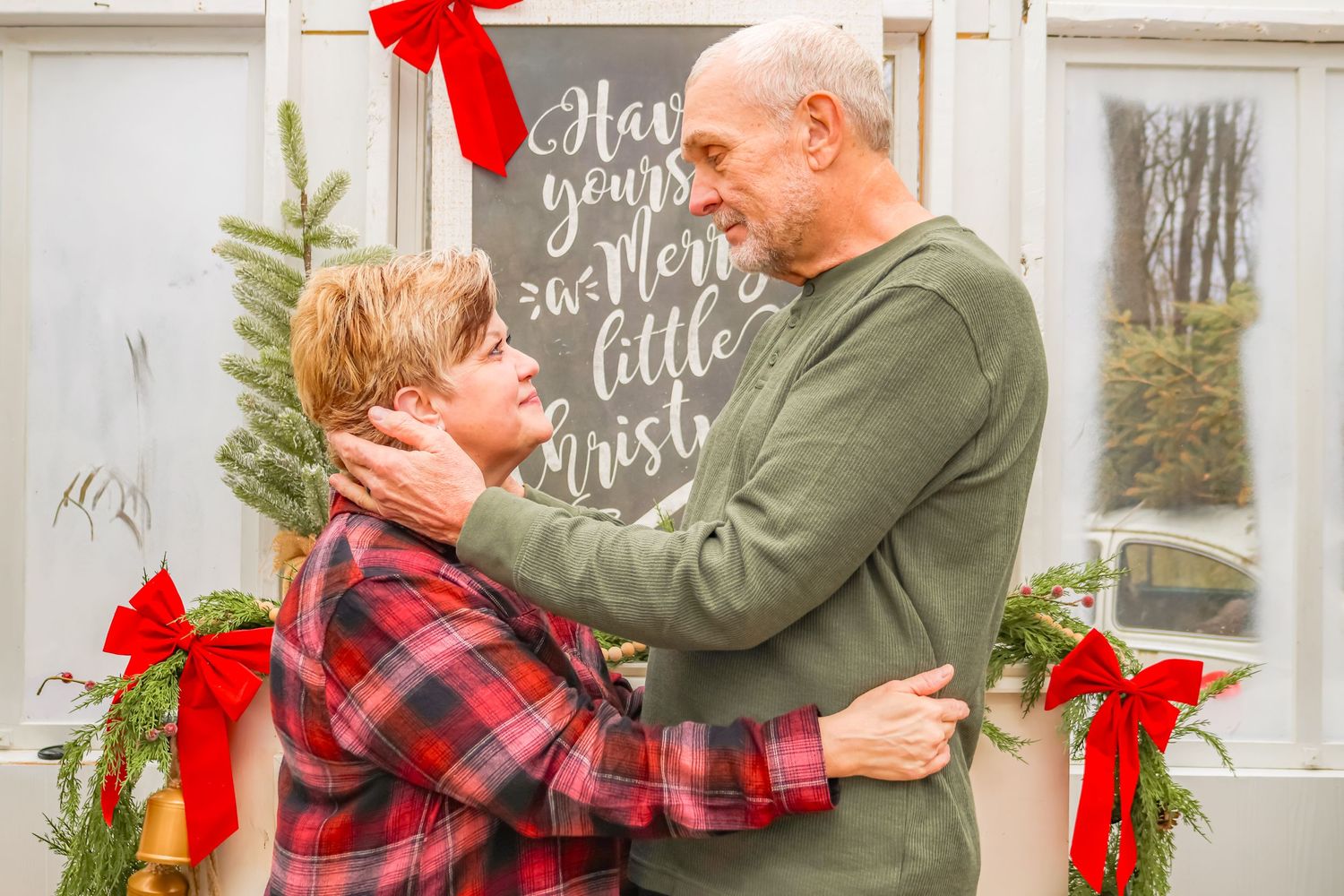 Sweet embrace in front of holiday chalkboard with Christmas decorations and red bows.