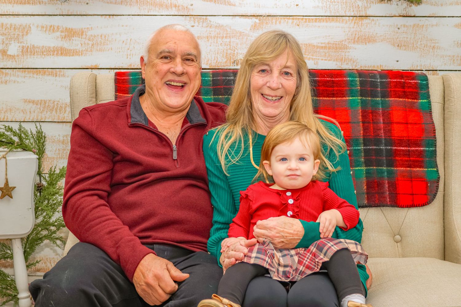A festive holiday photo on a beige couch with plaid tartan blanket and Christmas decorations in the background.