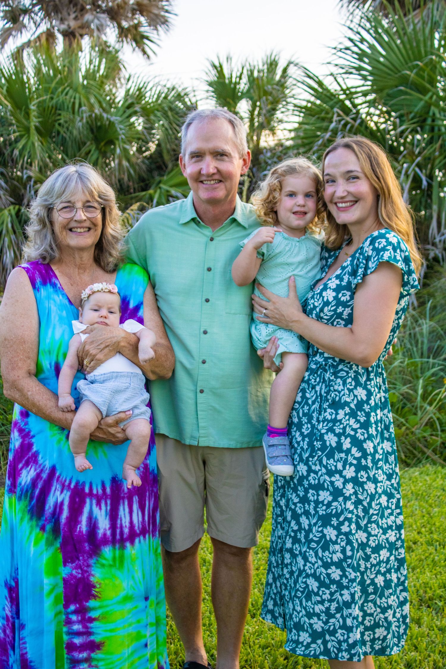 Multi-generational family portrait with grandmother, grandfather and young children in tropical setting.