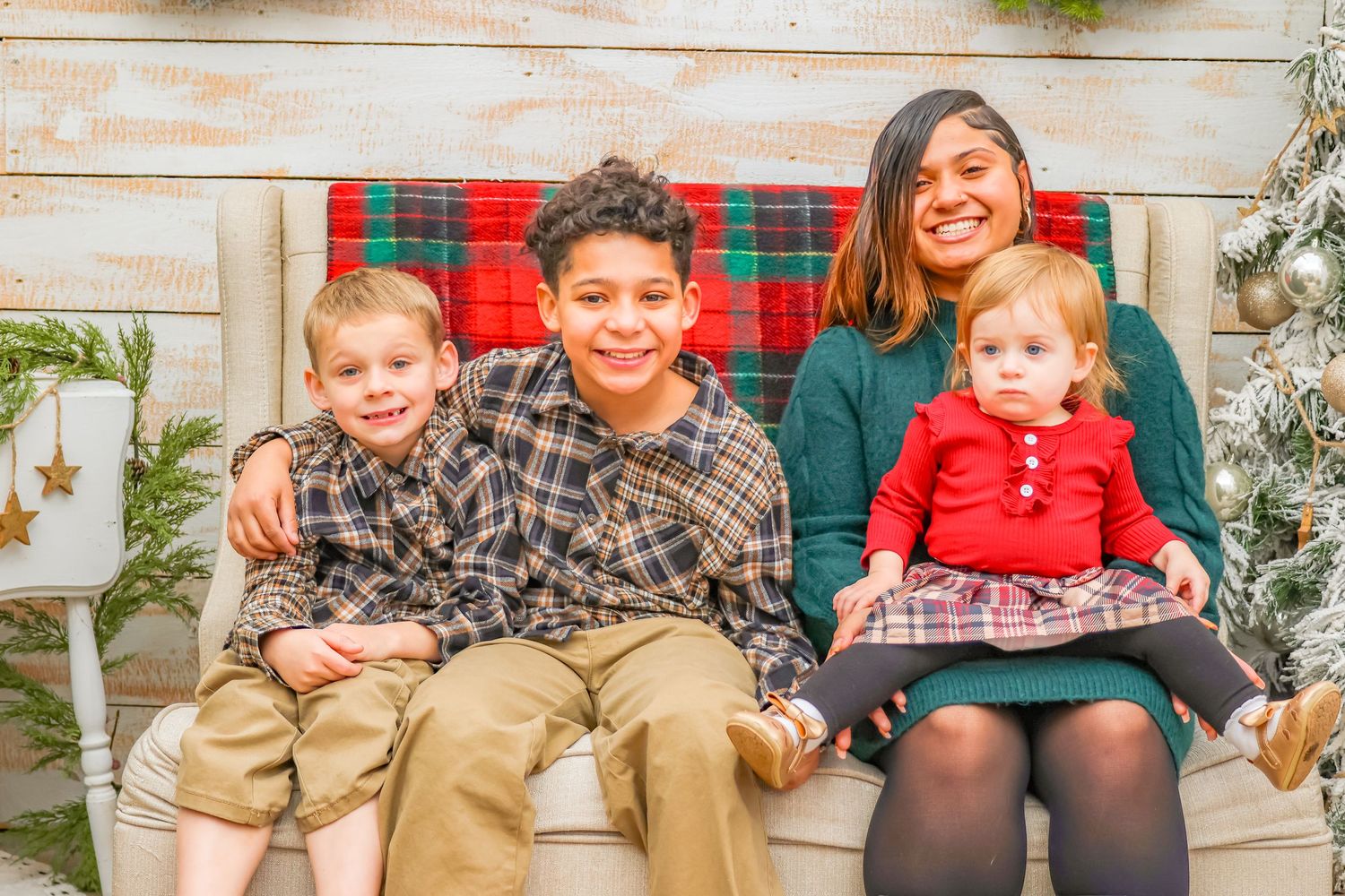 Holiday family portrait with plaid bench and festive Christmas decorations.