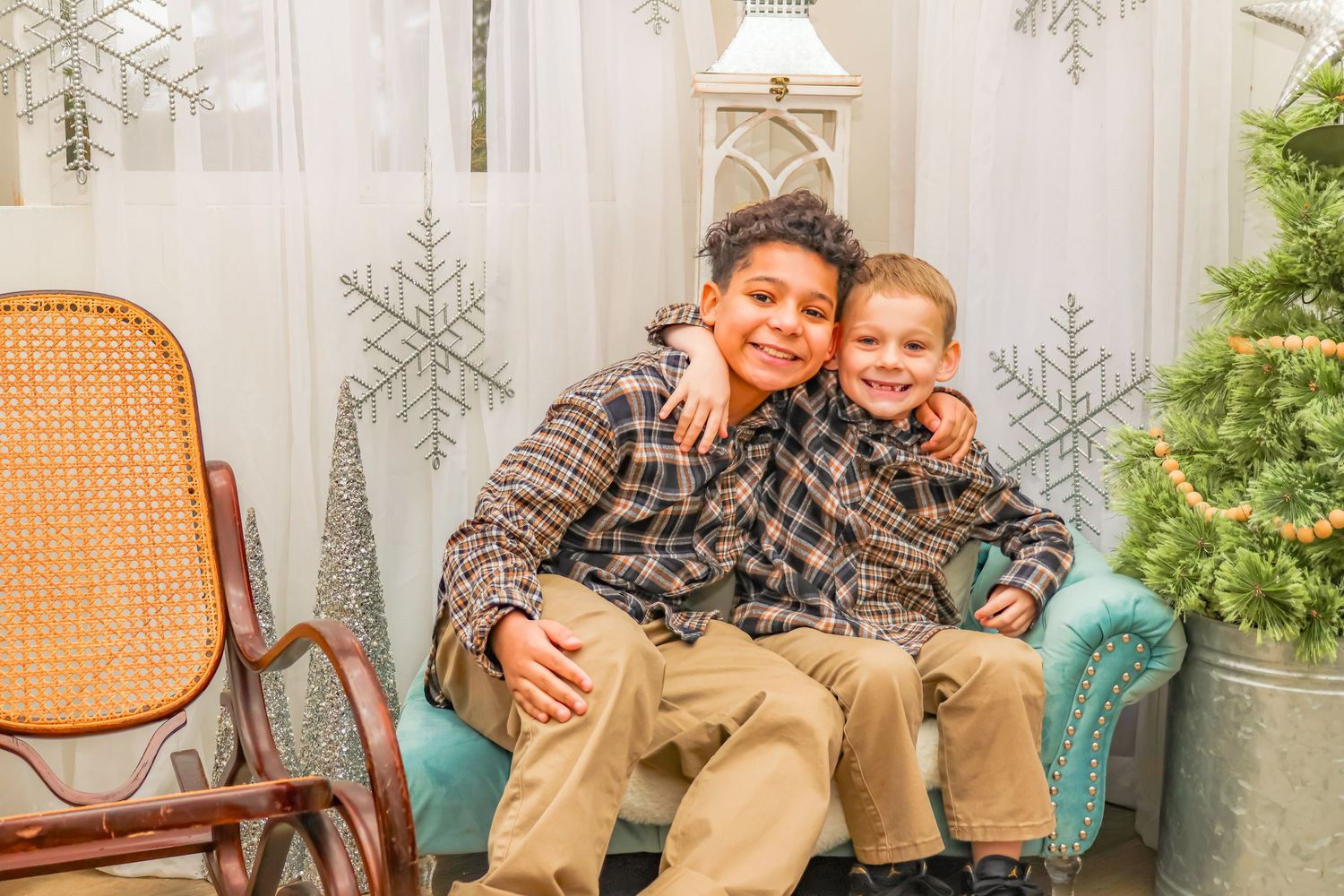 Two people sitting together on a blue chair with Christmas decorations visible.